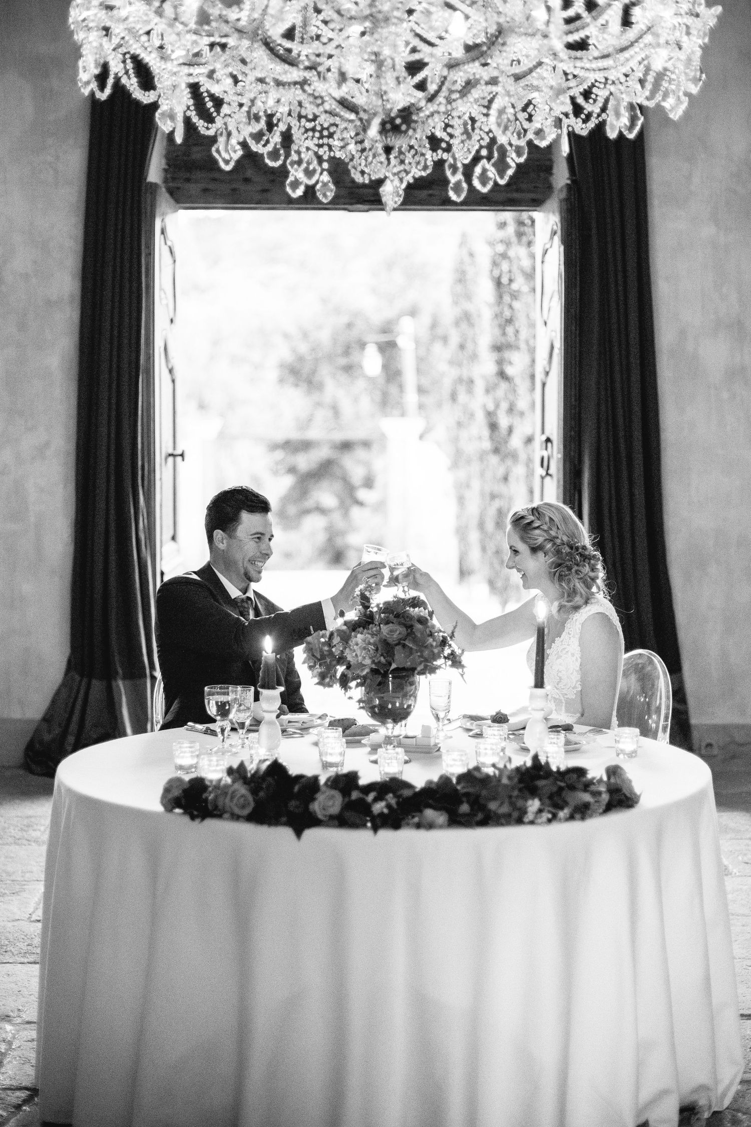 Romantic wedding toast under a crystal chandelier at an elegantly set sweetheart table at chateau de moissac in provence france.