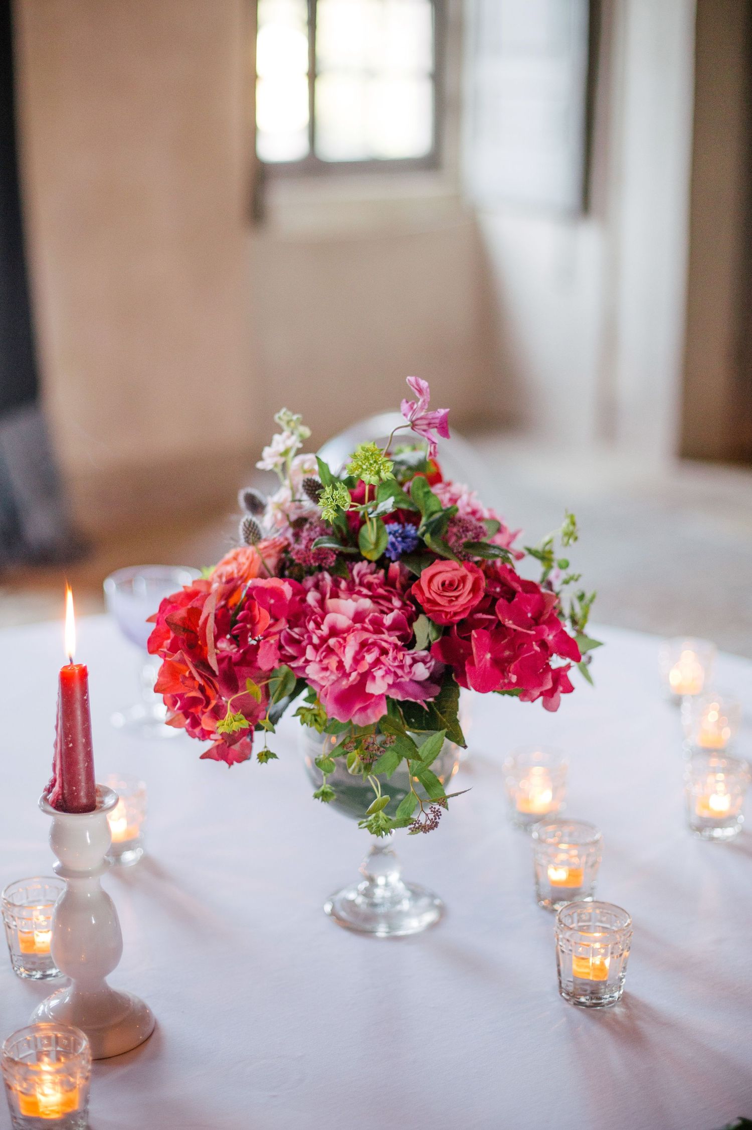 Romantic table centerpiece of pink roses and candles in elegant silver compote.