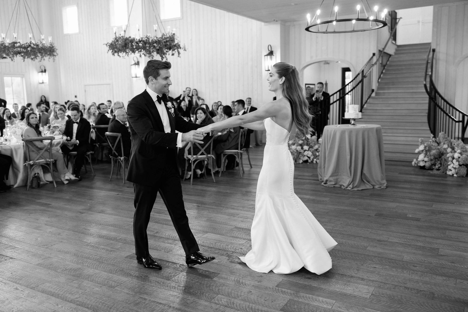 Couples dancing gracefully across a wooden ballroom floor during an elegant wedding reception celebration.