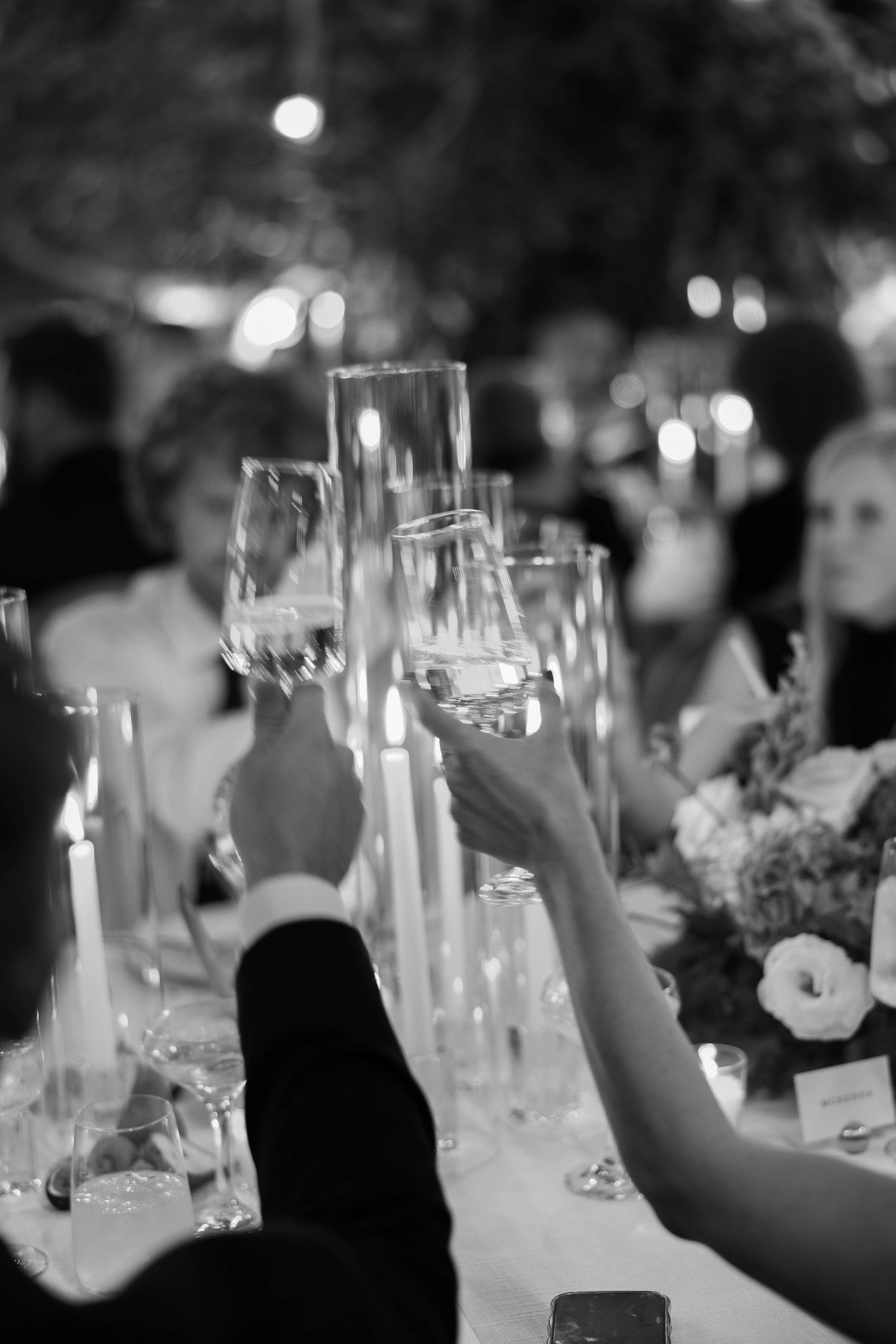 Wedding guests raising champagne glasses in candlelit reception celebration.
