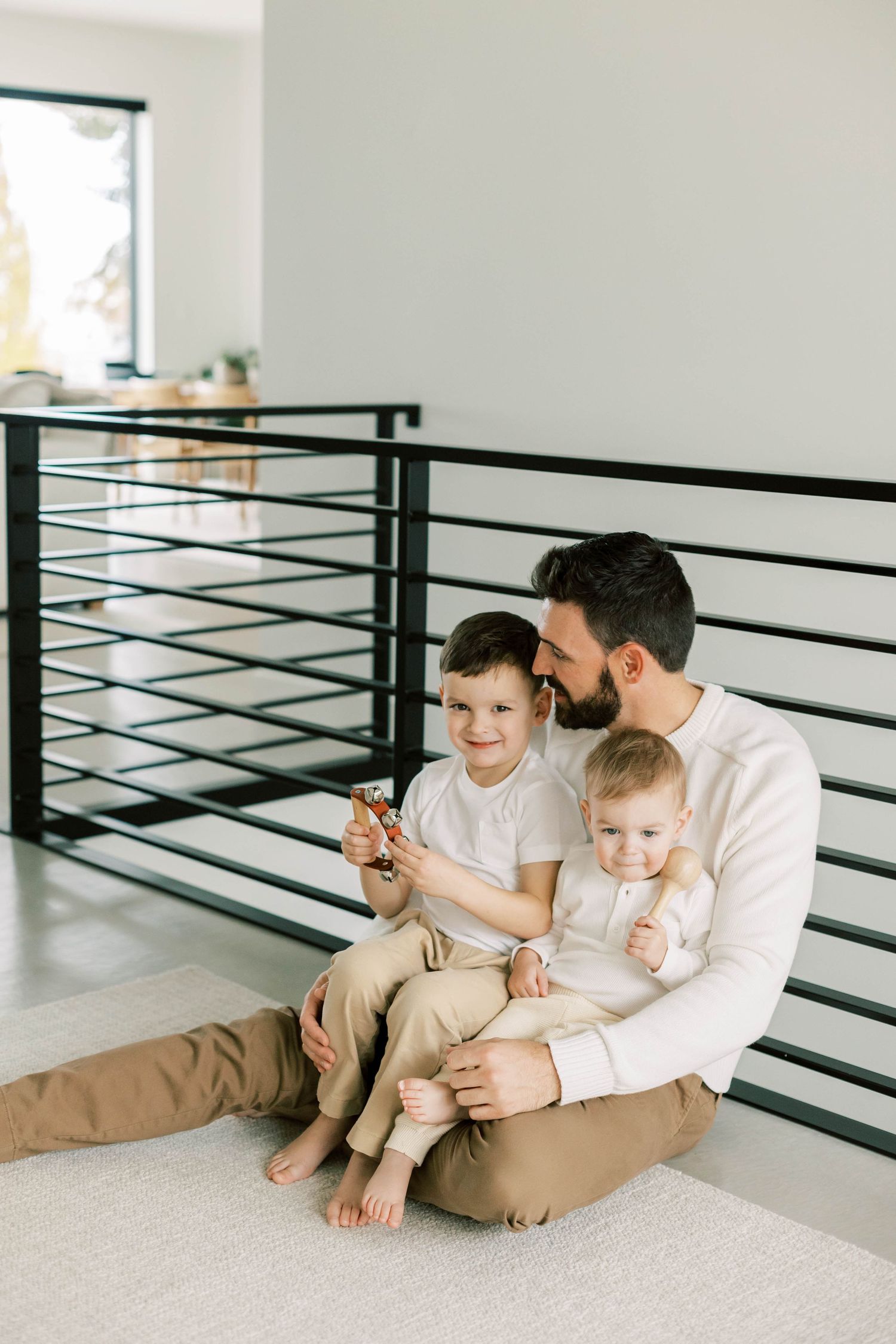Parent and children sitting on floor against modern railing sharing a quiet moment together.
