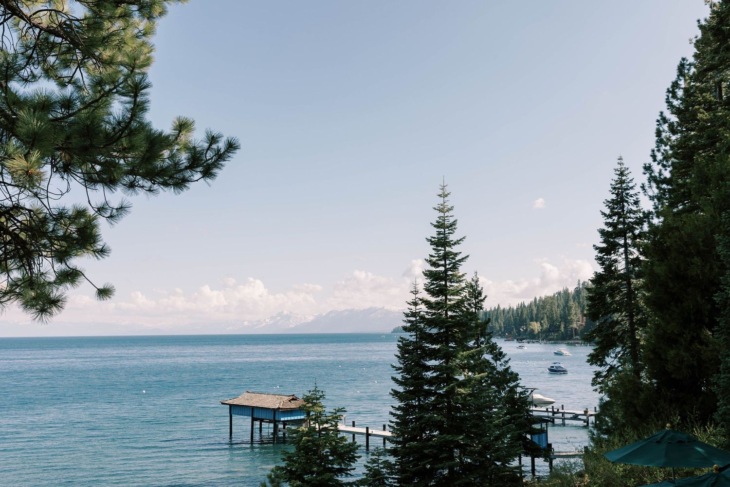 Scenic view of Lake Tahoe with a wooden pier and evergreen trees framing the blue water.