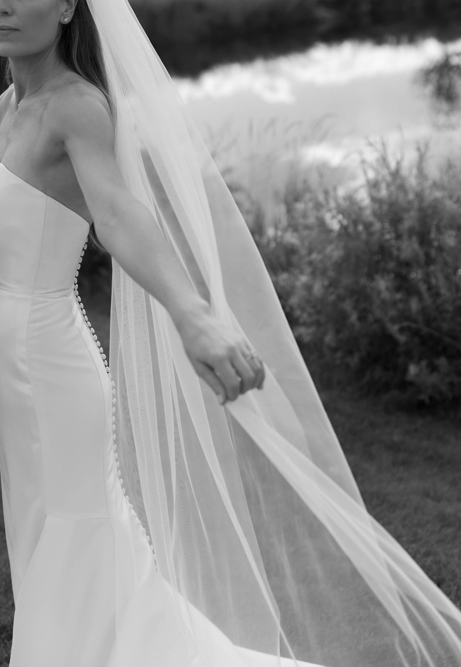 Close-up detail of flowing white wedding dress with delicate veil in black and white.
