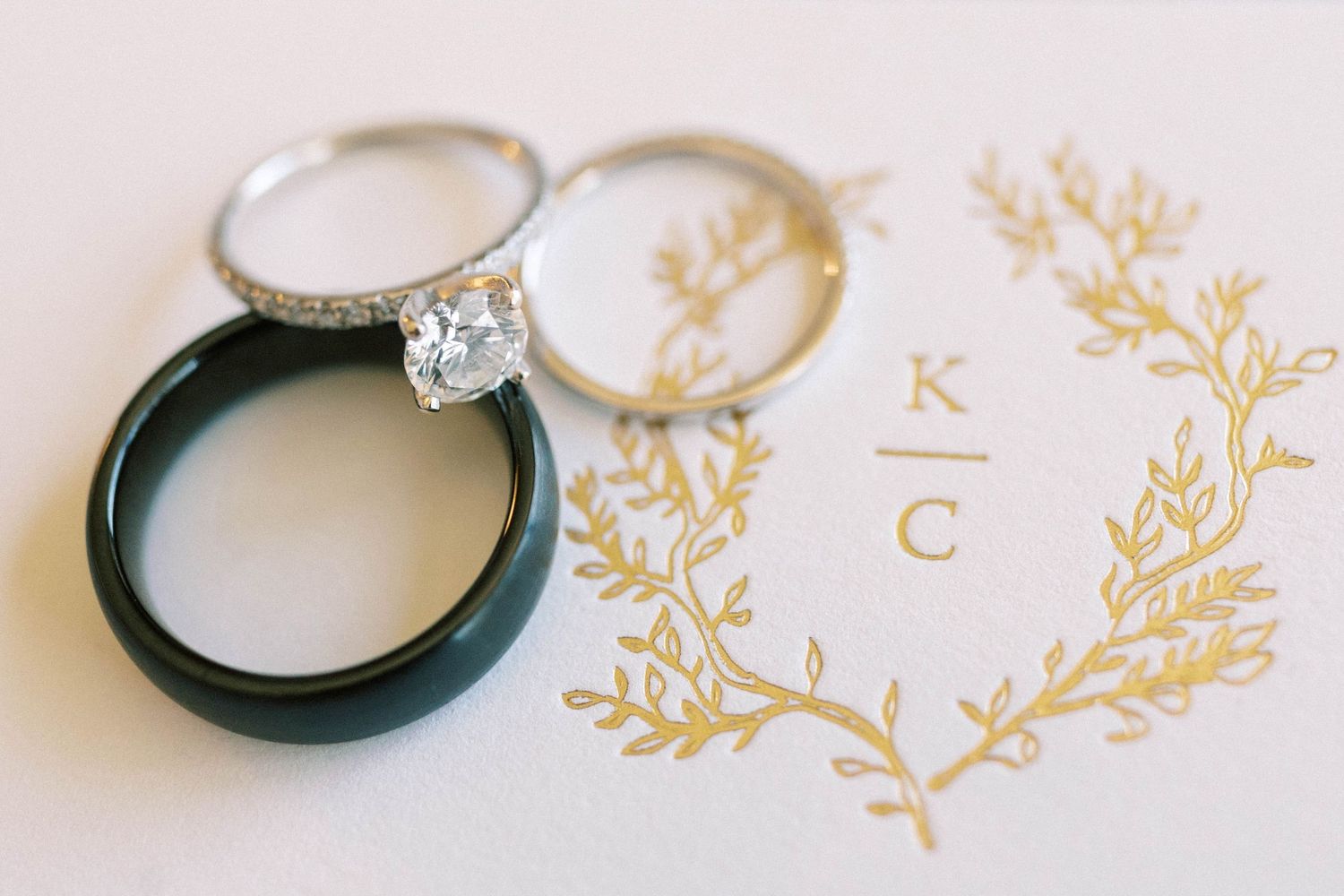 Wedding rings and gold monogram detail on elegant stationery.