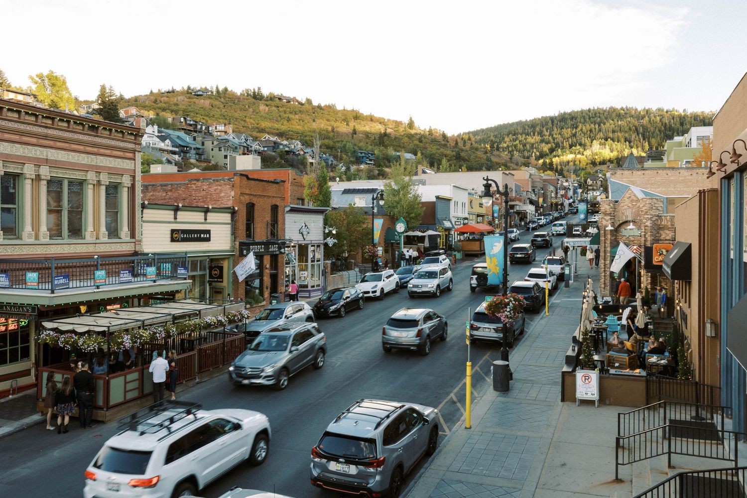 Main Street in Park City Utah shows bustling traffic and historic buildings nestled against mountain slopes at dusk.