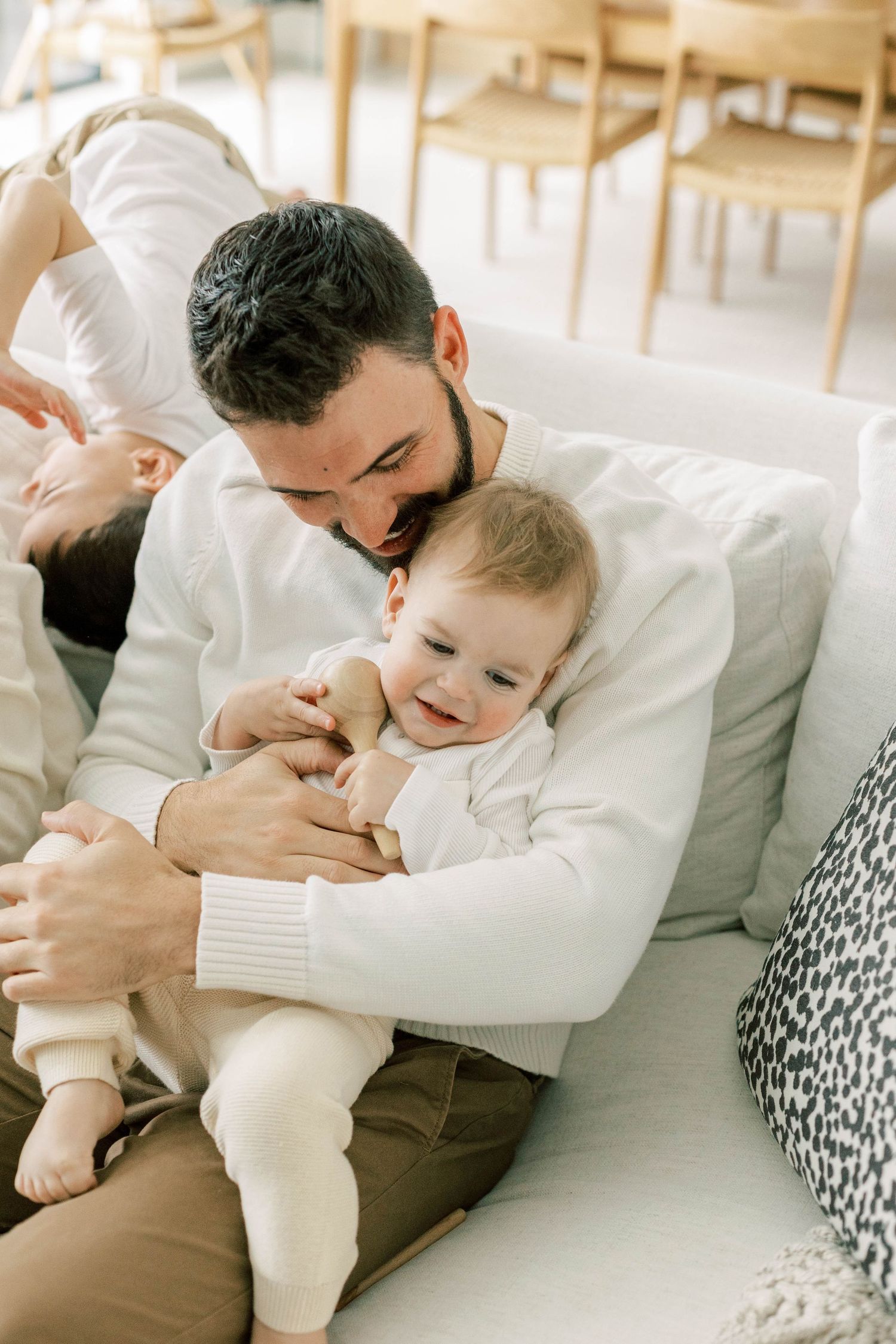 Sweet moment between parent and baby on white sofa in modern living room setting.