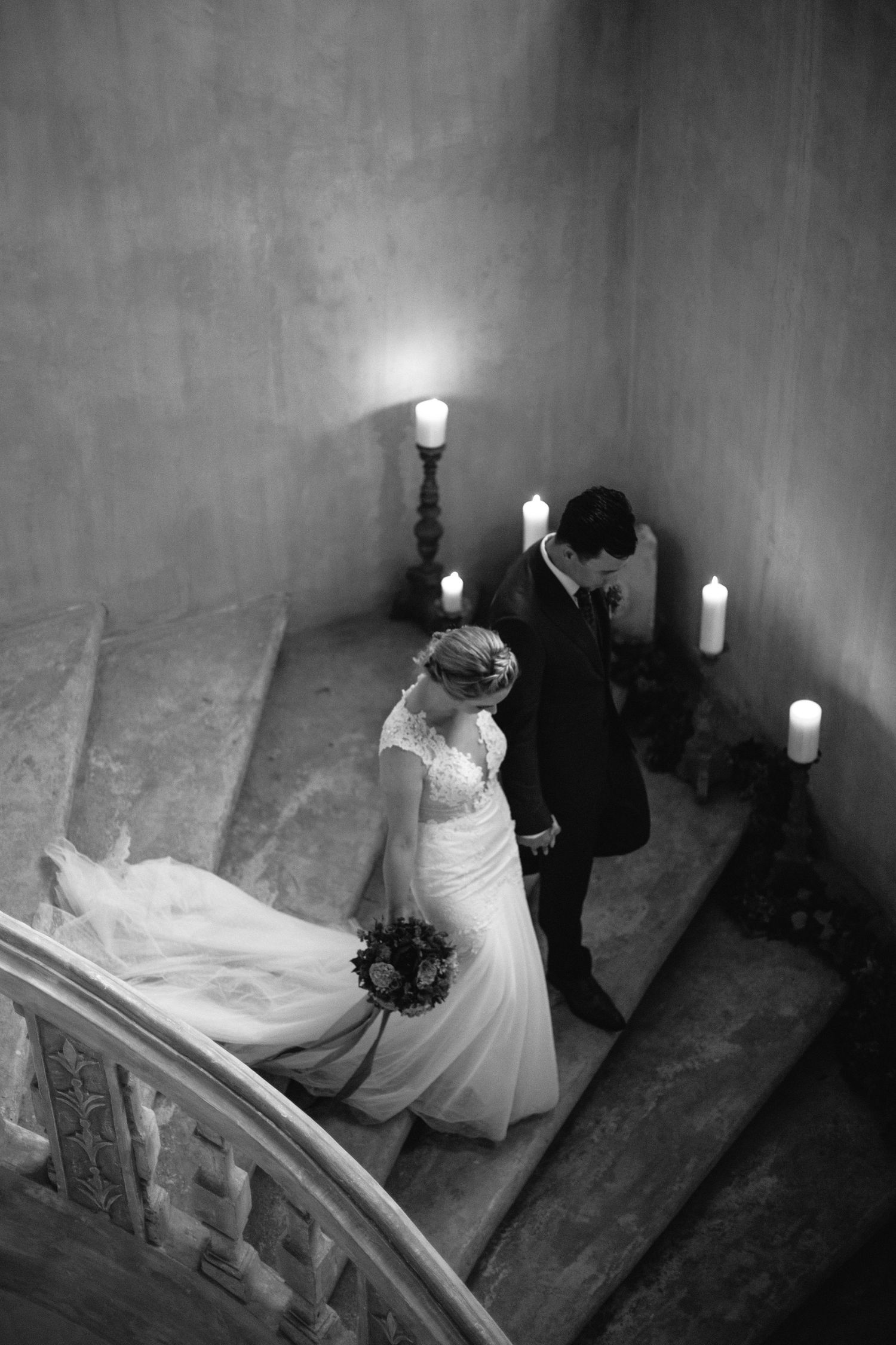 Romantic black and white photo of a couple descending candlelit stone stairs.