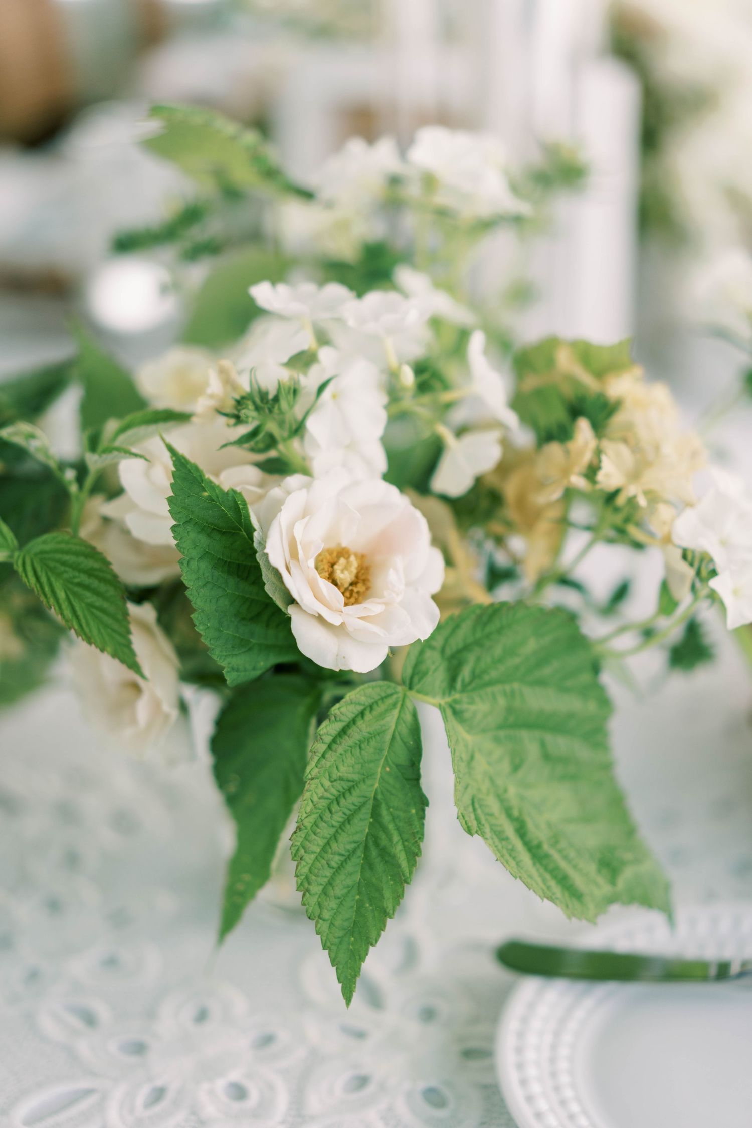 Close-up of white garden roses and greenery in wedding centerpiece arrangement.