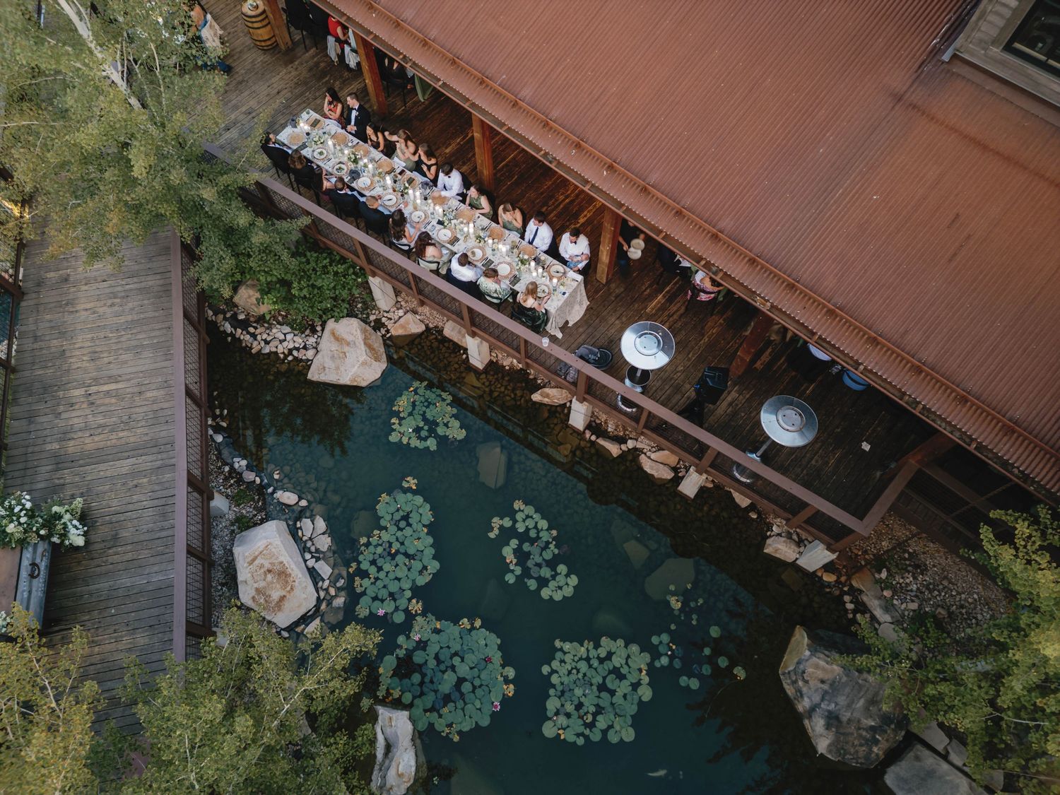 Aerial view of a wooden dock extending over turquoise water with trees and foliage along the shoreline.