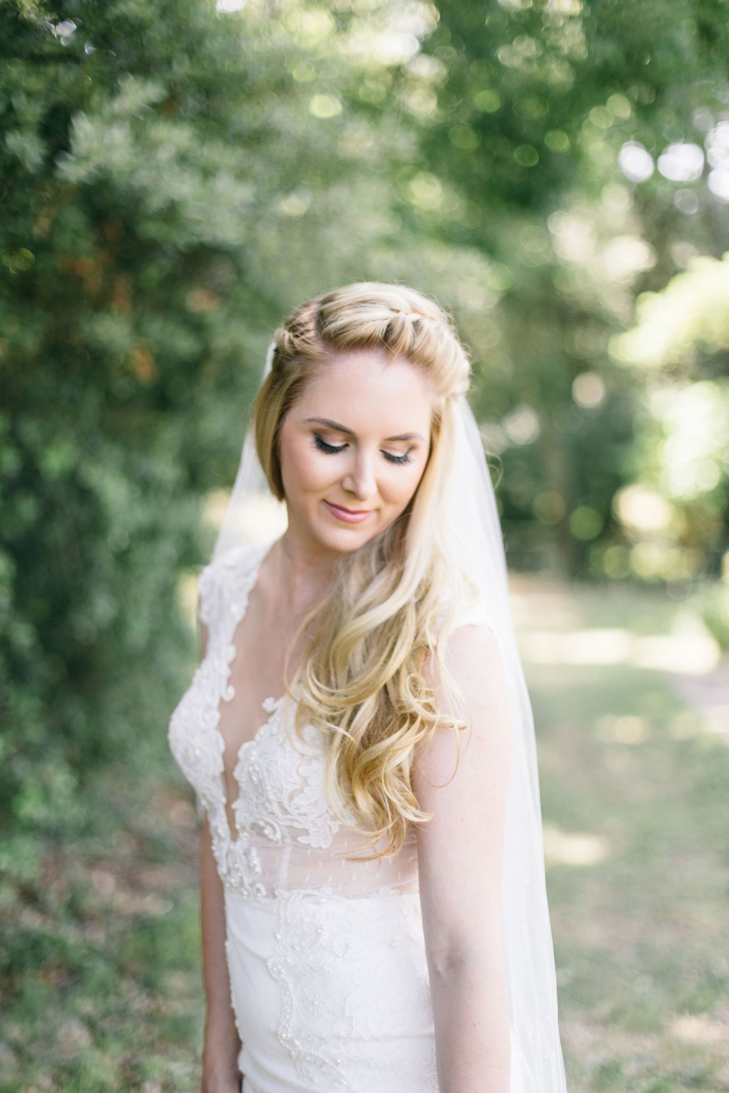 A delicate lace wedding dress with flowing veil captured in soft natural lighting.