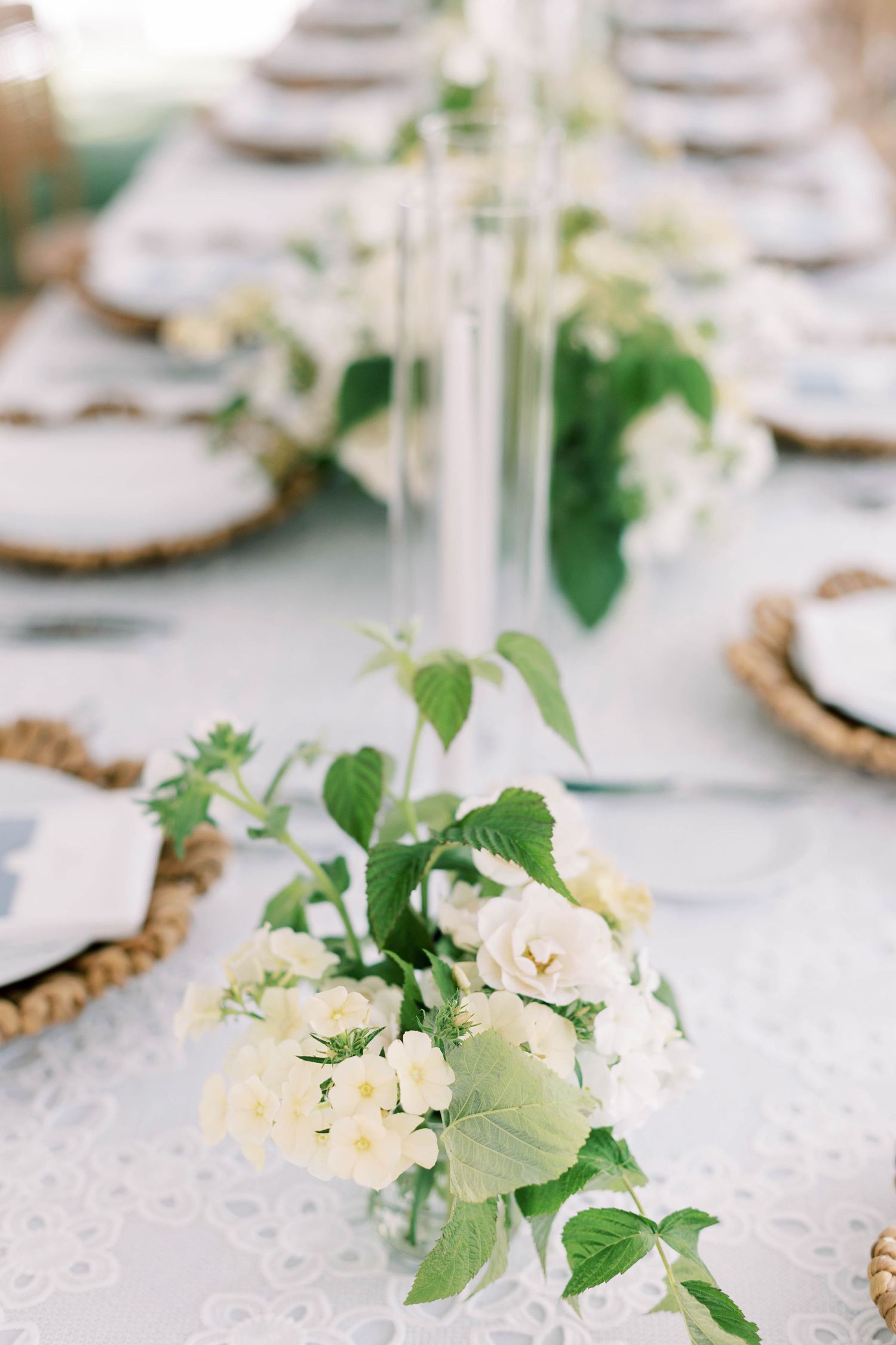 Delicate white floral table arrangements on a lace-covered wedding reception table.