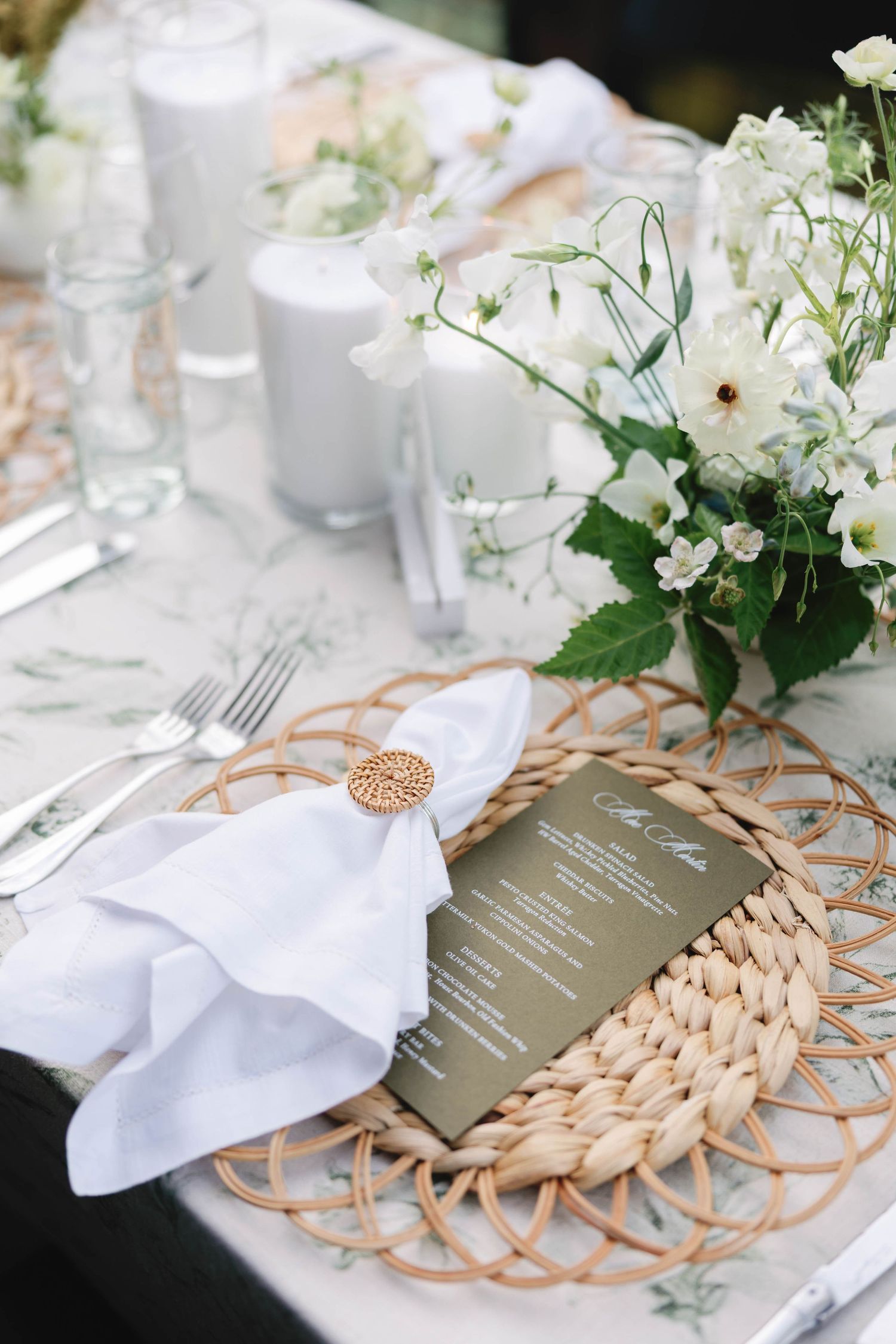 Elegant table setting with woven chargers, white napkins, and delicate floral centerpieces.