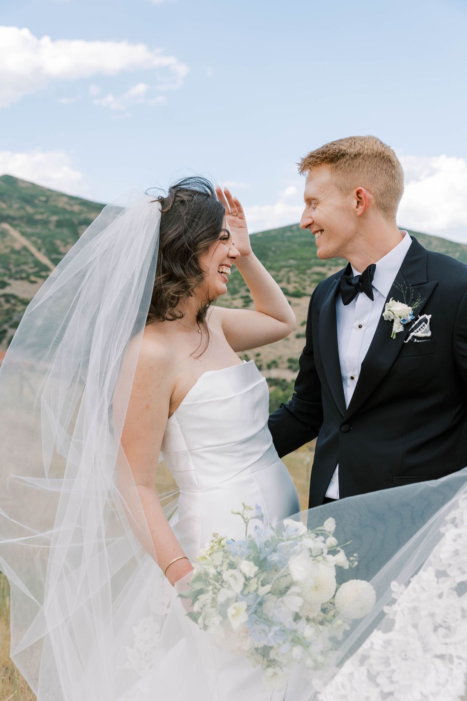 Newlyweds share tender moments against a mountain backdrop on their wedding day.