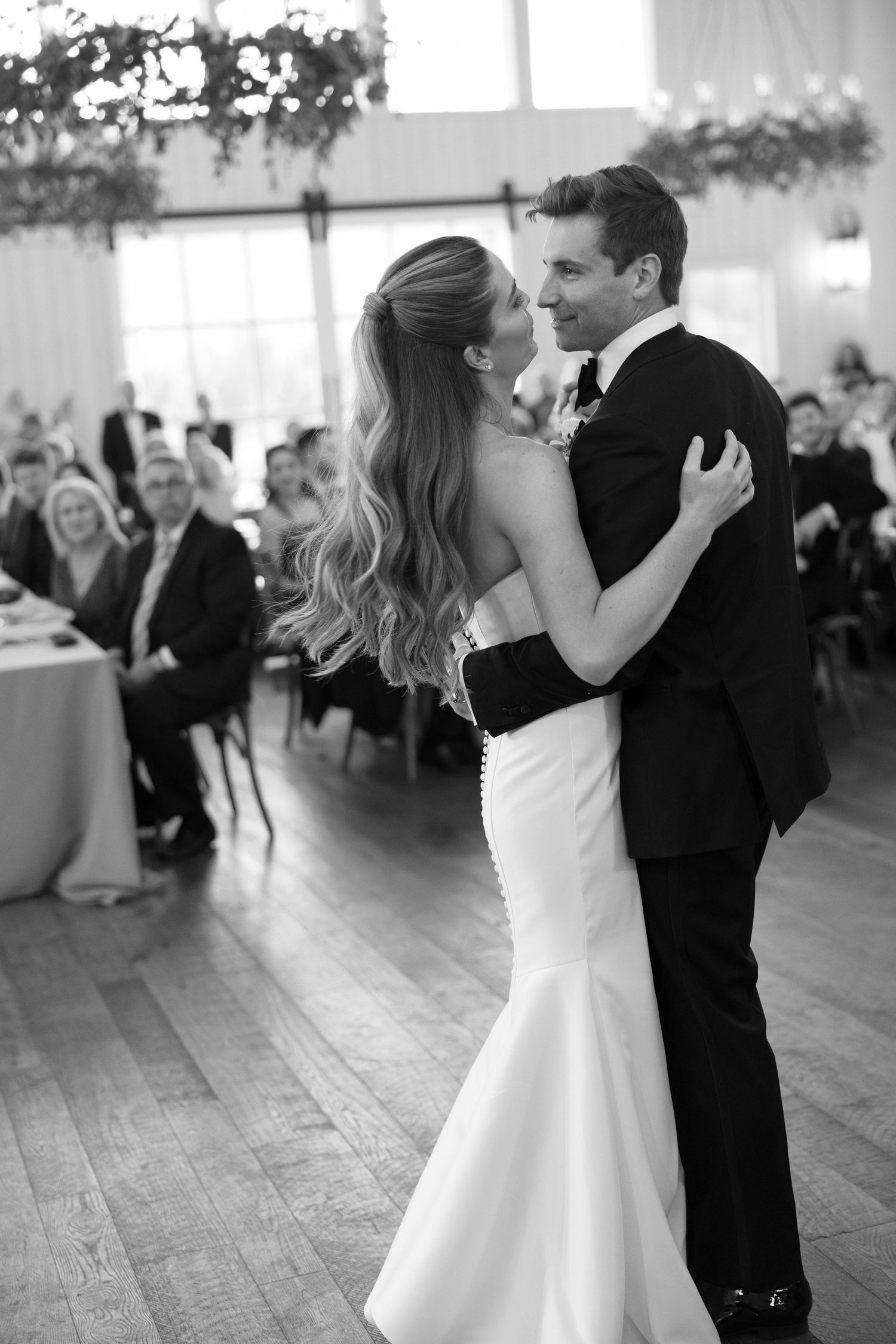 A romantic first dance sequence between newlyweds at their wedding reception in a bright ballroom.