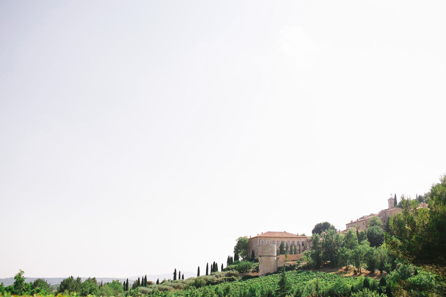 Hilltop Mediterranean villa surrounded by cypress trees and rolling countryside.