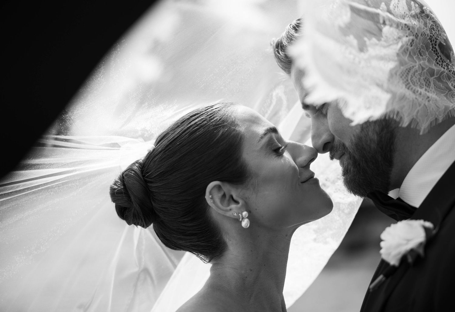 Black and white close up of a romantic wedding couple sharing an intimate moment with bride wearing veil.