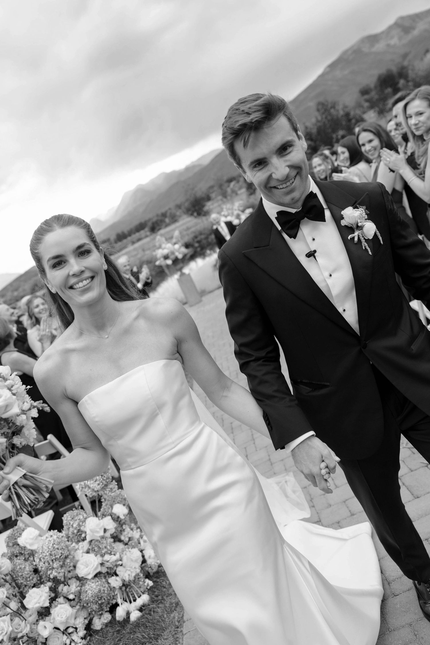 Wedding couple shares joyful moments with mountain scenery in the background.