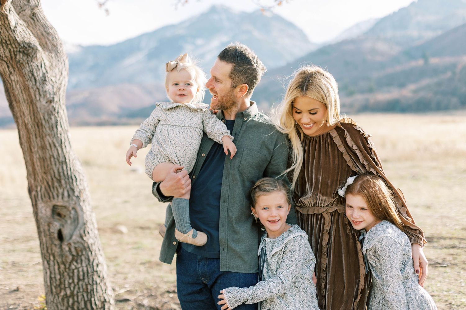Casual outdoor family portrait beneath old tree in  Utah mountain field during autumn.