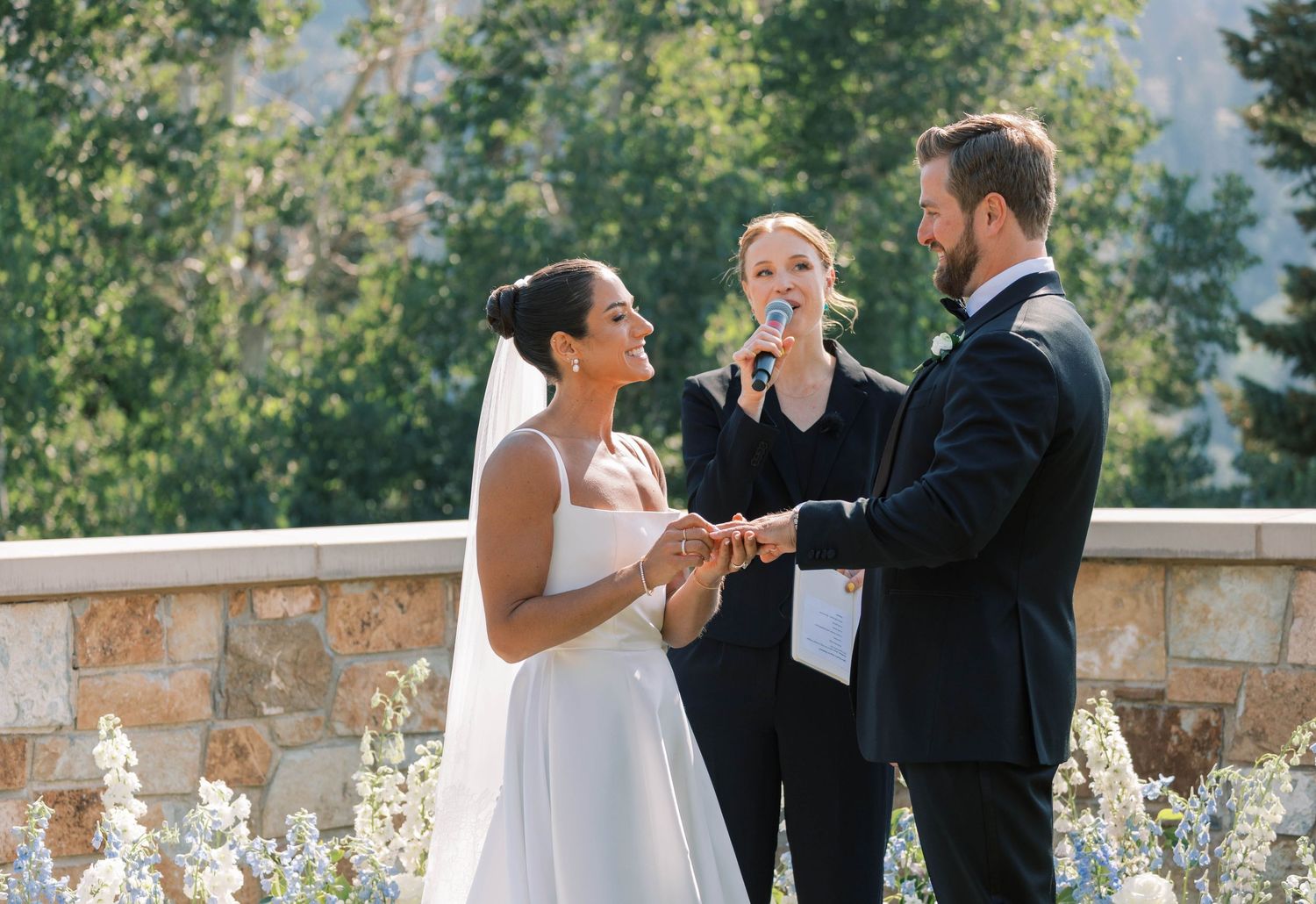 Wedding ceremony taking place outdoors on a stone terrace with mountain views in the background.