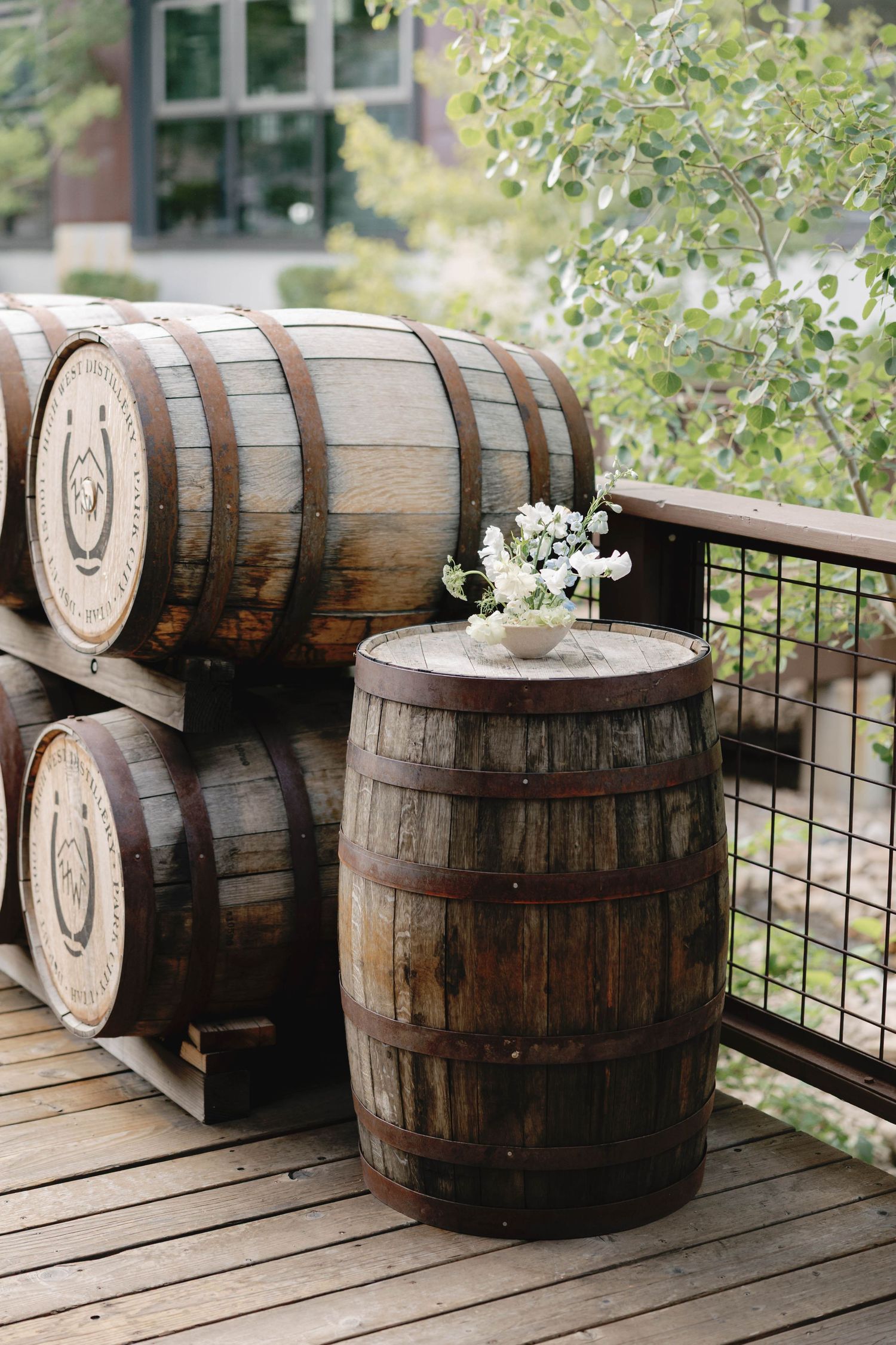 Rustic wooden whiskey barrels decorated with small white flowers on a wooden deck.