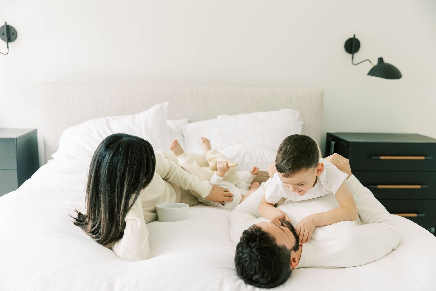 Happy family sharing playful moment together on cozy white bed.