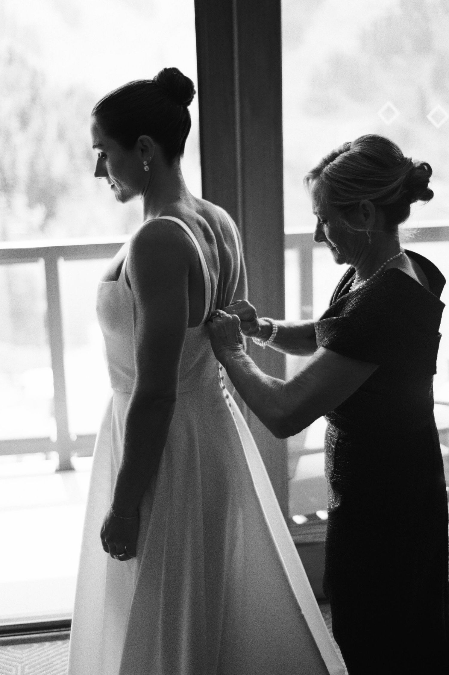 Black and white silhouettes of bridesmaids helping the bride prepare for her wedding ceremony.