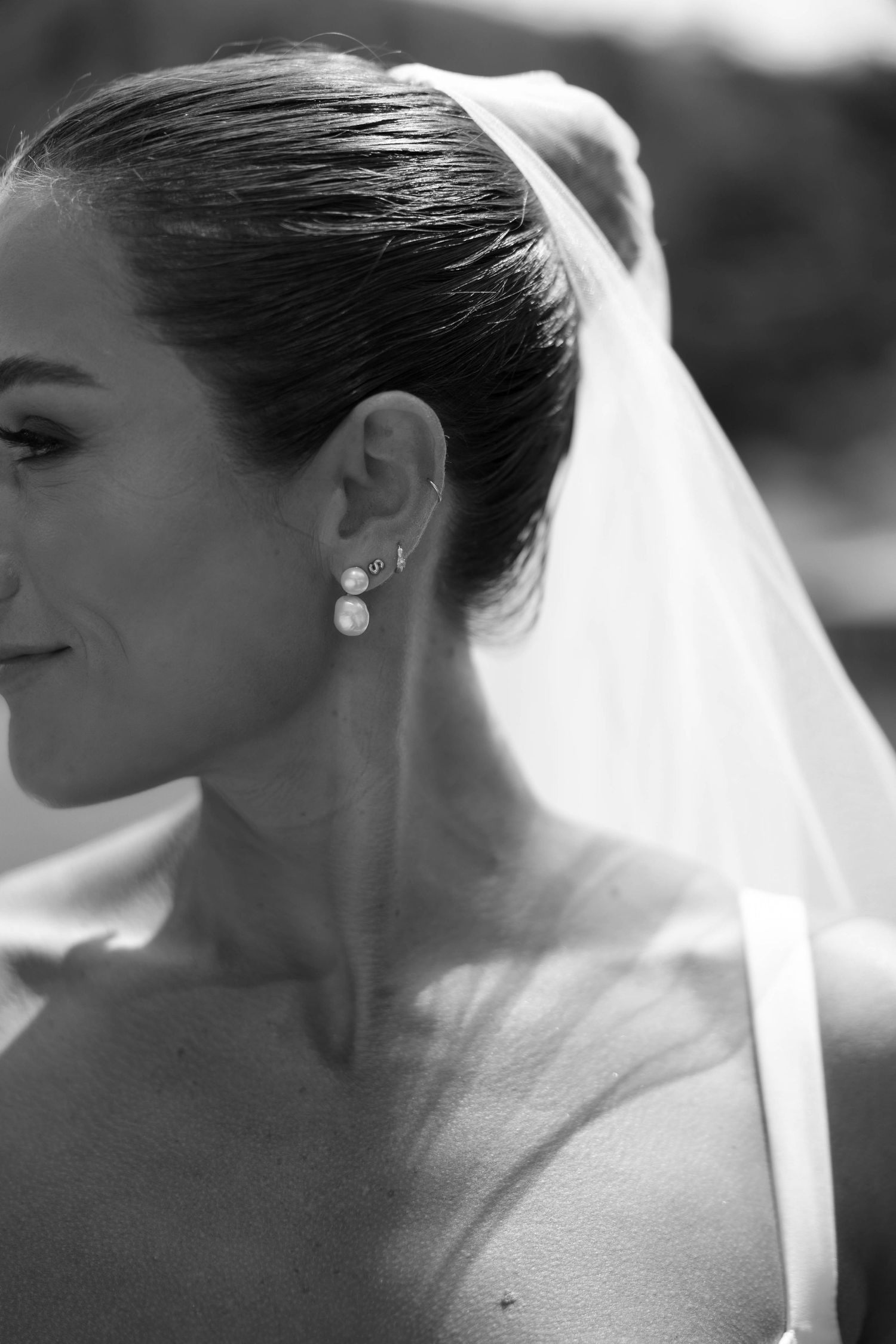 Black and white profile portrait showing delicate bridal veil and pearl earring details.