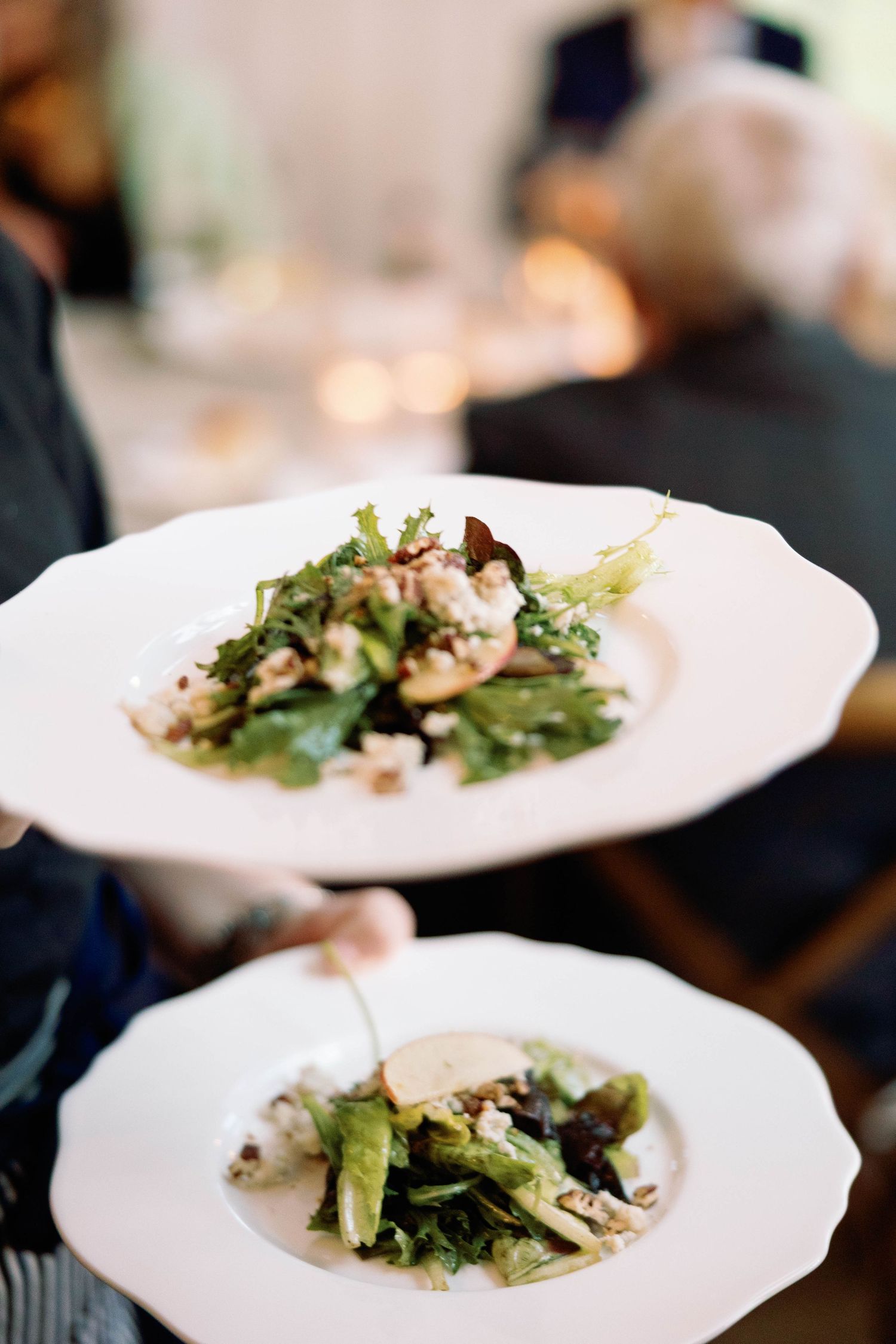 Fresh green salad plates with mixed greens and toppings arranged on white dishes at a restaurant table.