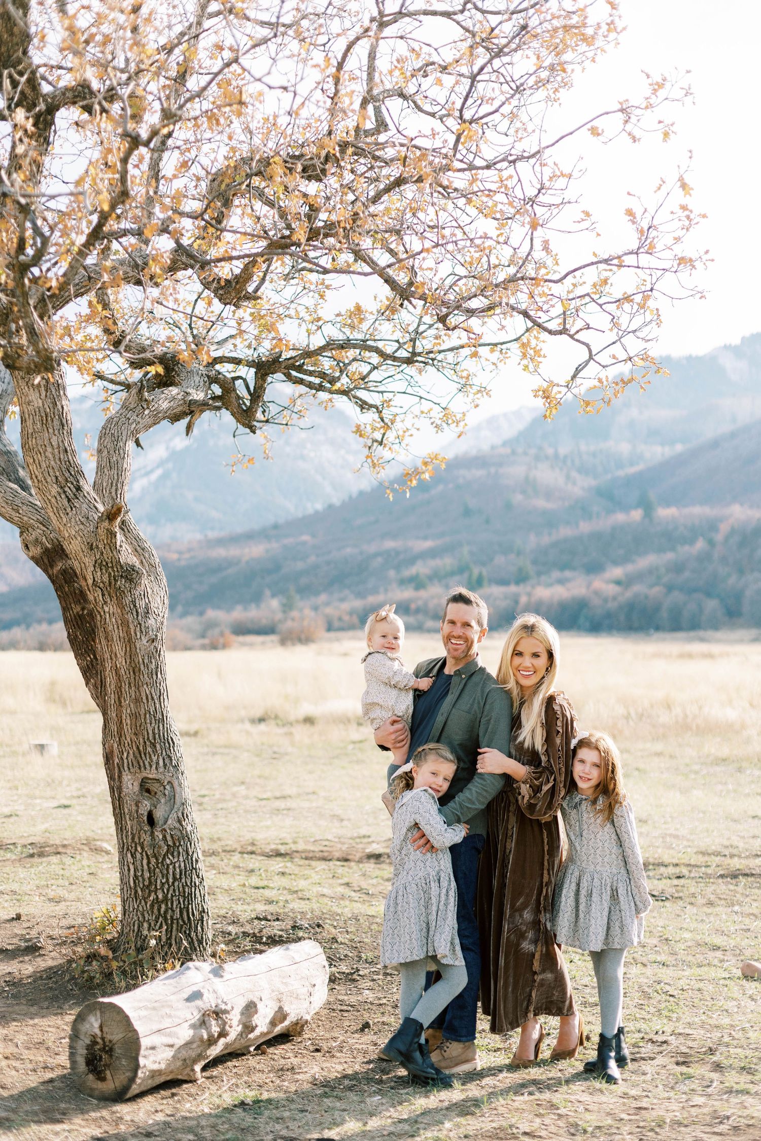 Family portrait under twisted tree in Utah mountain meadow during golden hour.