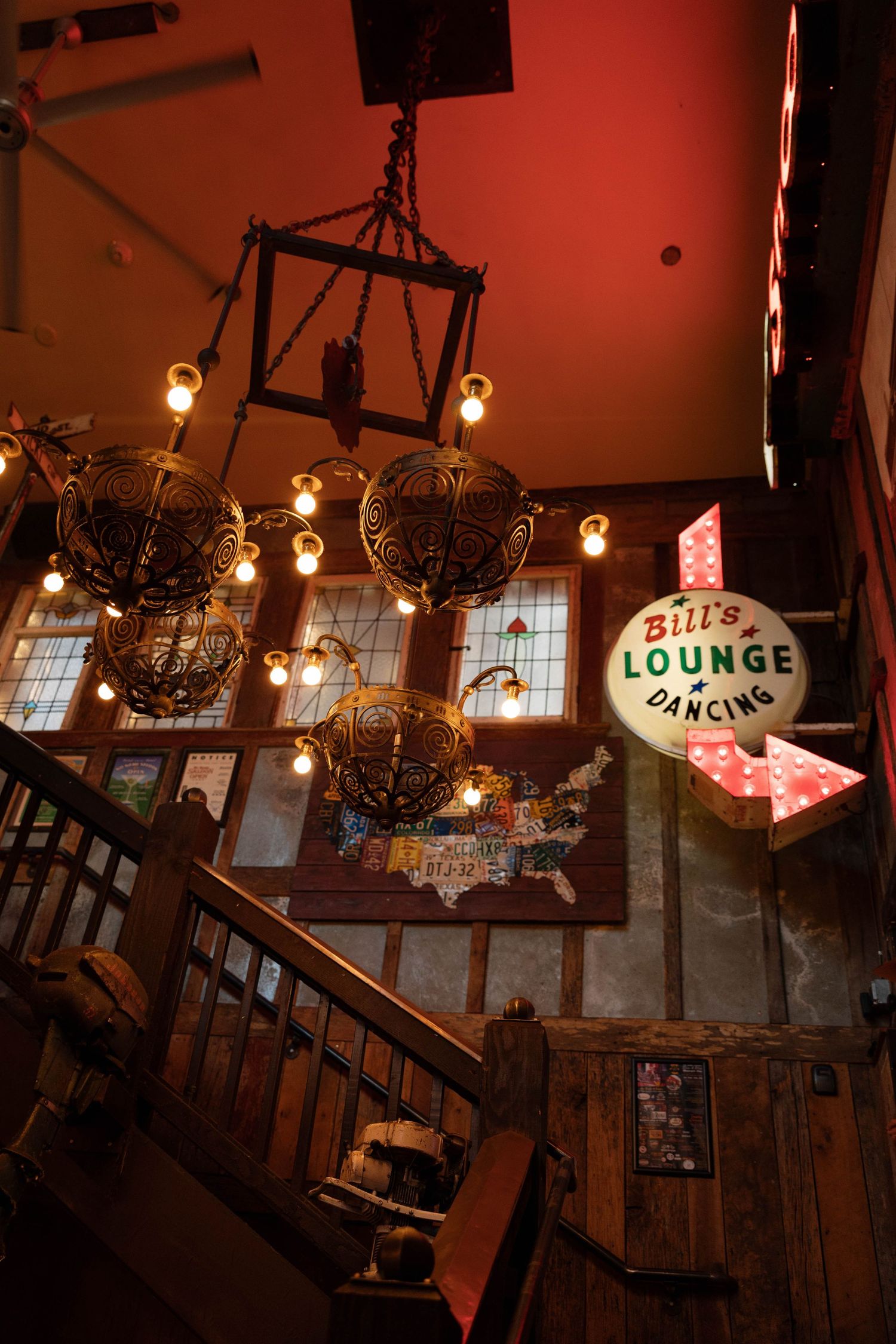 Vintage bar interior with red lighting and neon signs showing Bill's Lounge.