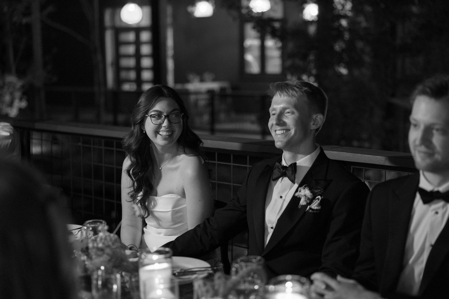 Wedding reception guests seated at tables with ambient lighting creating a warm atmosphere.