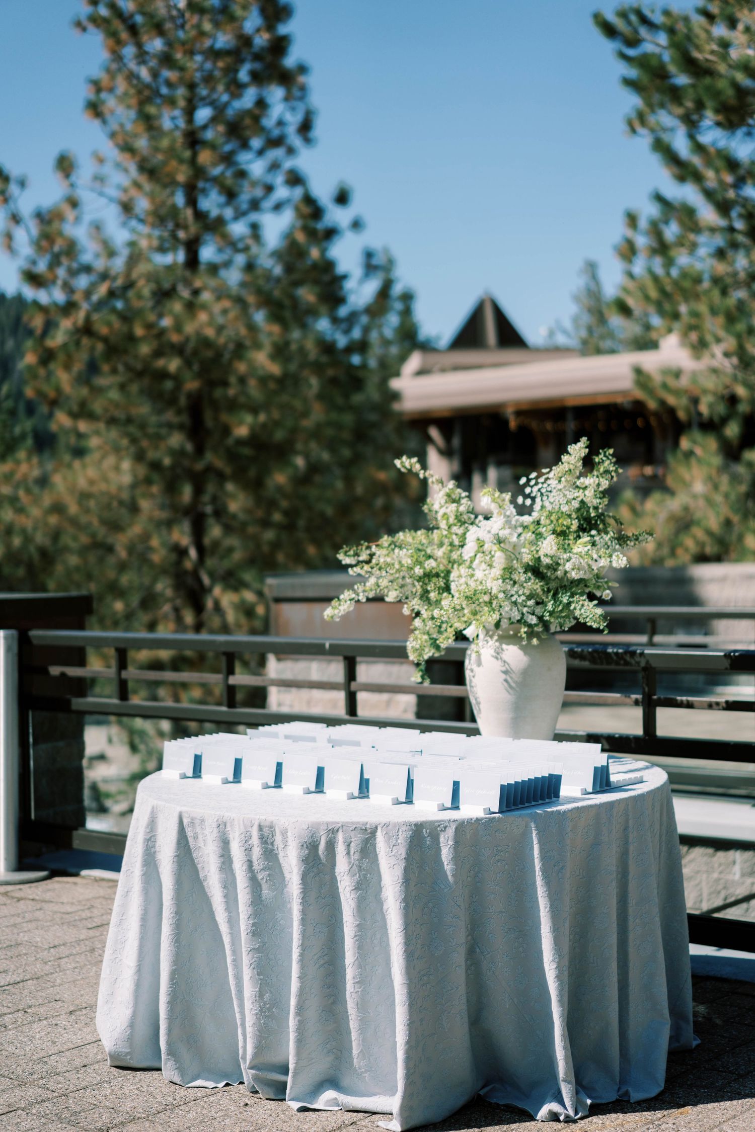 Wedding reception table with white linens and floral centerpiece against mountain backdrop.