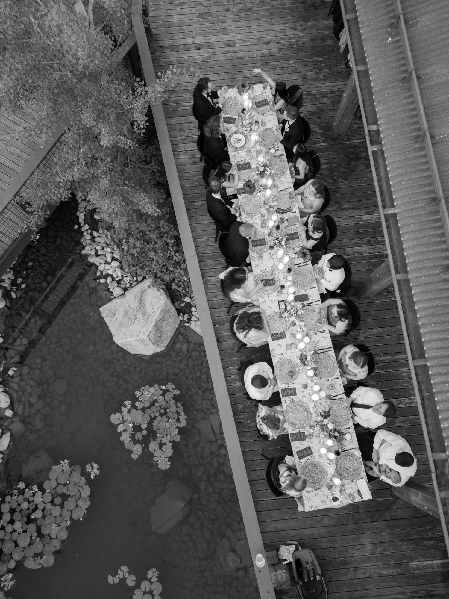 An overhead view of people seated around a long dining table with plates and decorative floral arrangements.
