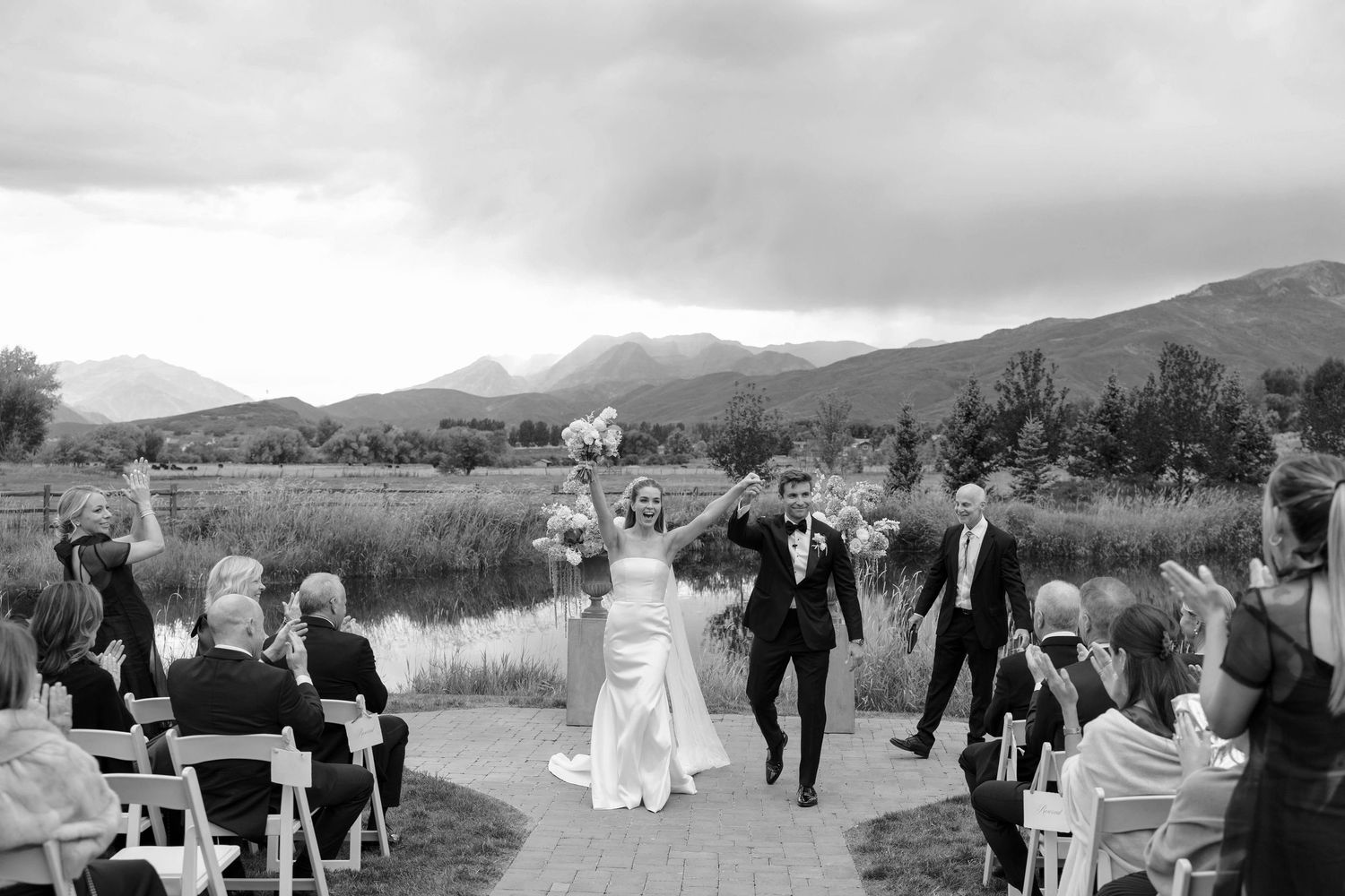Wedding party walks along a scenic mountain path in black and white photography.