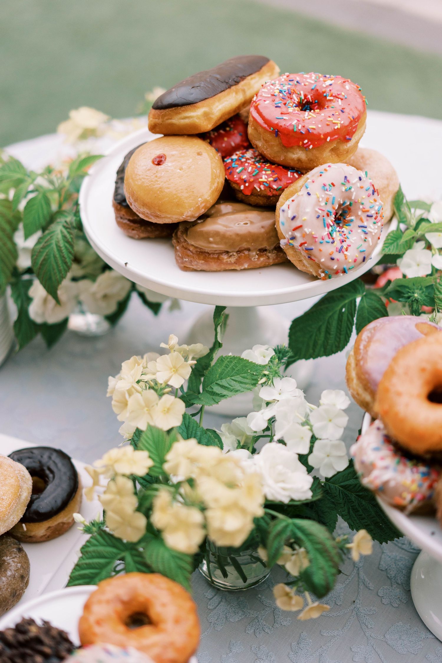 Colorful wedding dessert display featuring decorated donuts and white flowers.