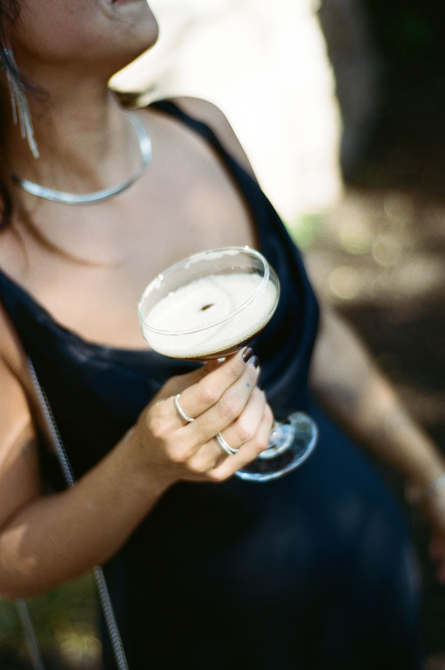 Close-up sequence of hands holding elegant cocktail glasses with white drinks at an upscale event.