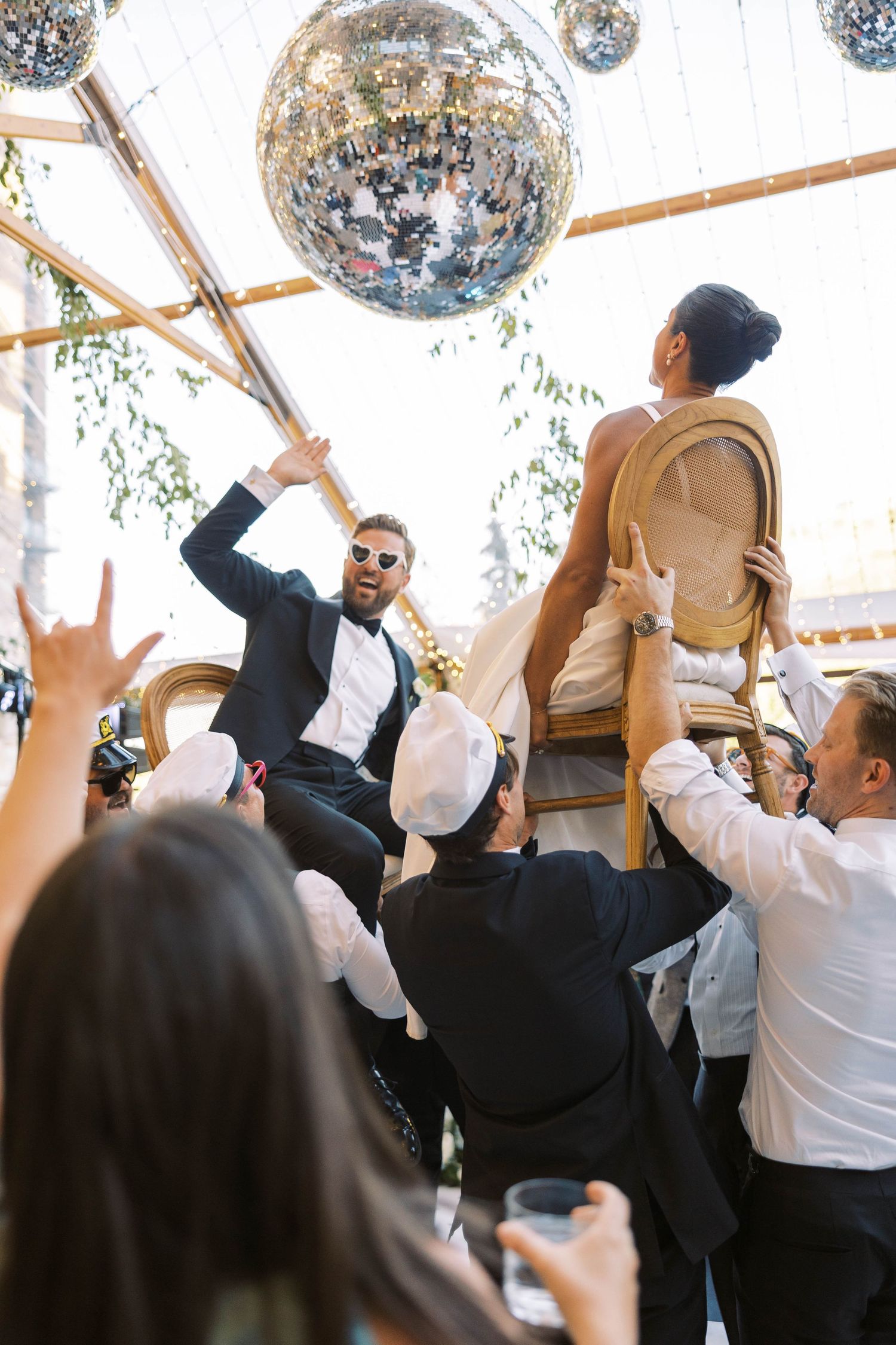 Wedding guests dancing under disco balls at a lively reception celebration.