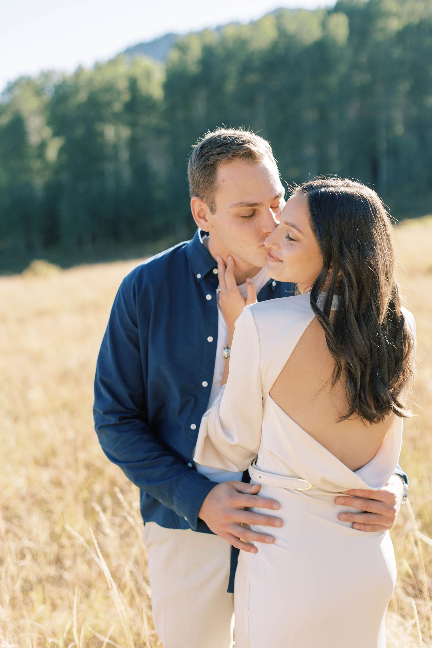 Tender embrace captured in golden mountain meadow during sunset.