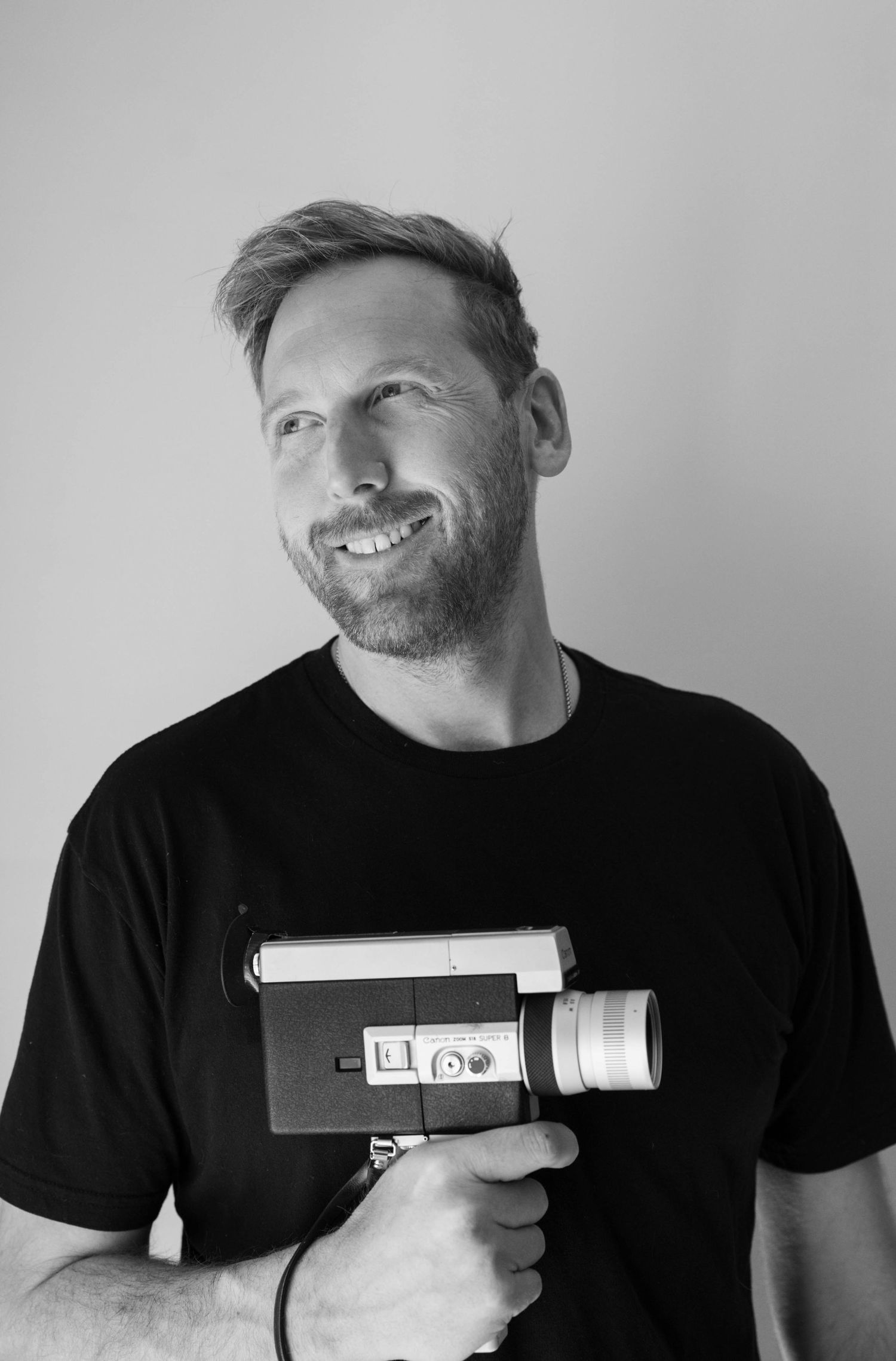 Black and white photo series showing someone in a dark shirt holding a handheld device in different poses.