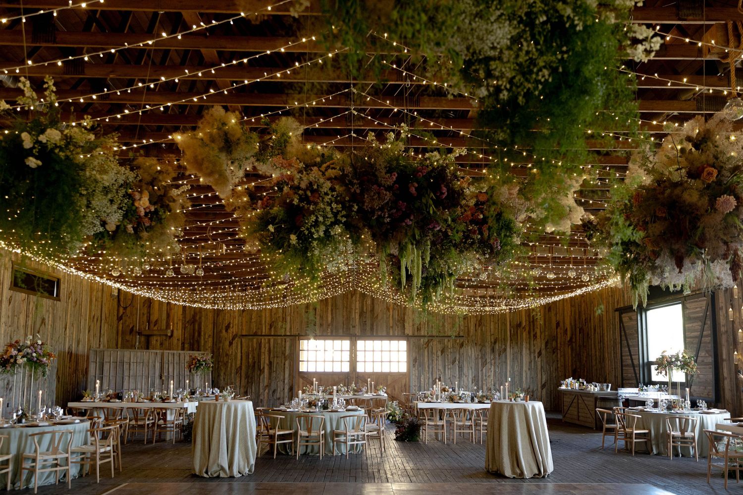 Rustic barn wedding venue decorated with twinkling string lights and greenery creating a magical indoor atmosphere.