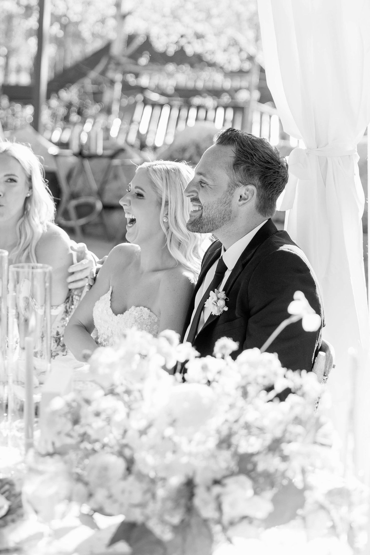 Wedding reception candid moment captured at the head table with floral decorations.