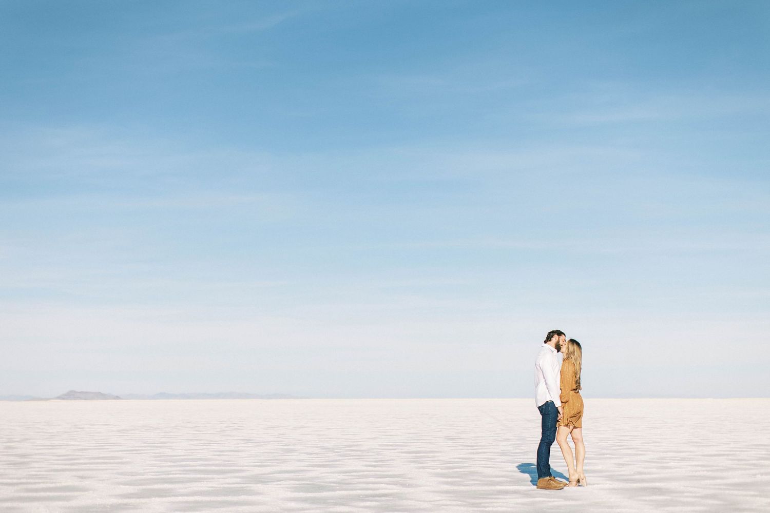 Minimalist composition of couple standing together on expansive white Utah salt flats.