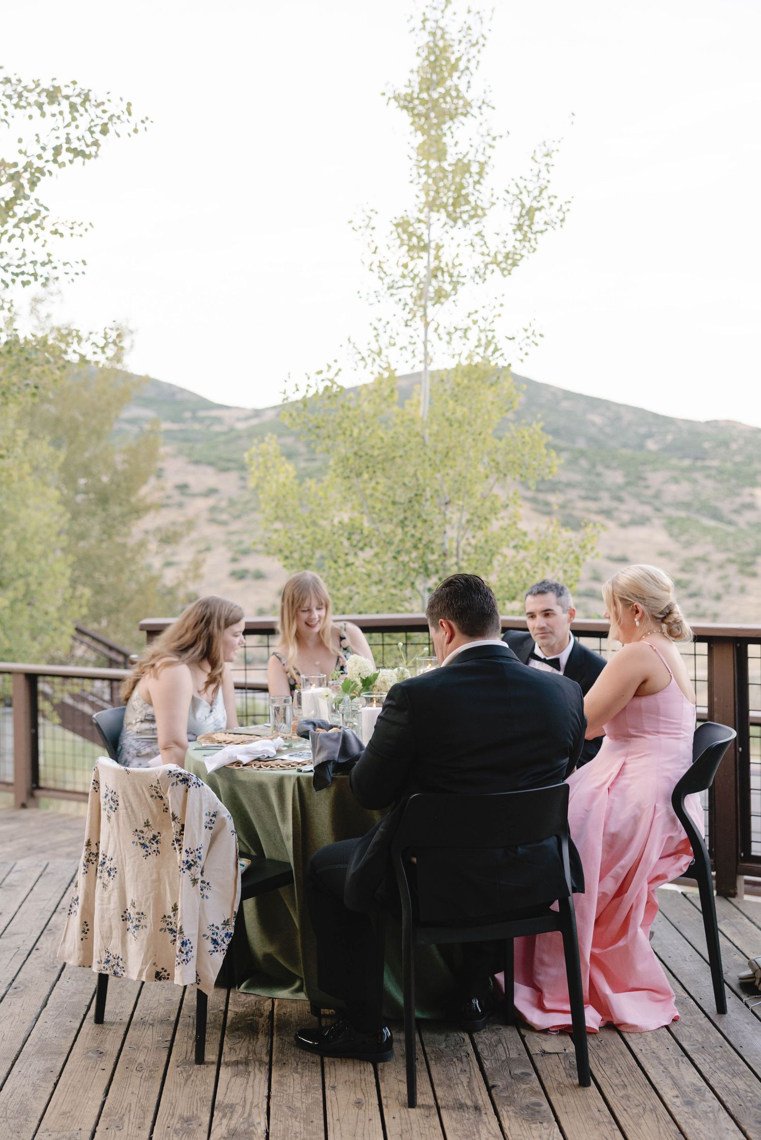 Wedding guests relax on an outdoor deck with mountain views at sunset.