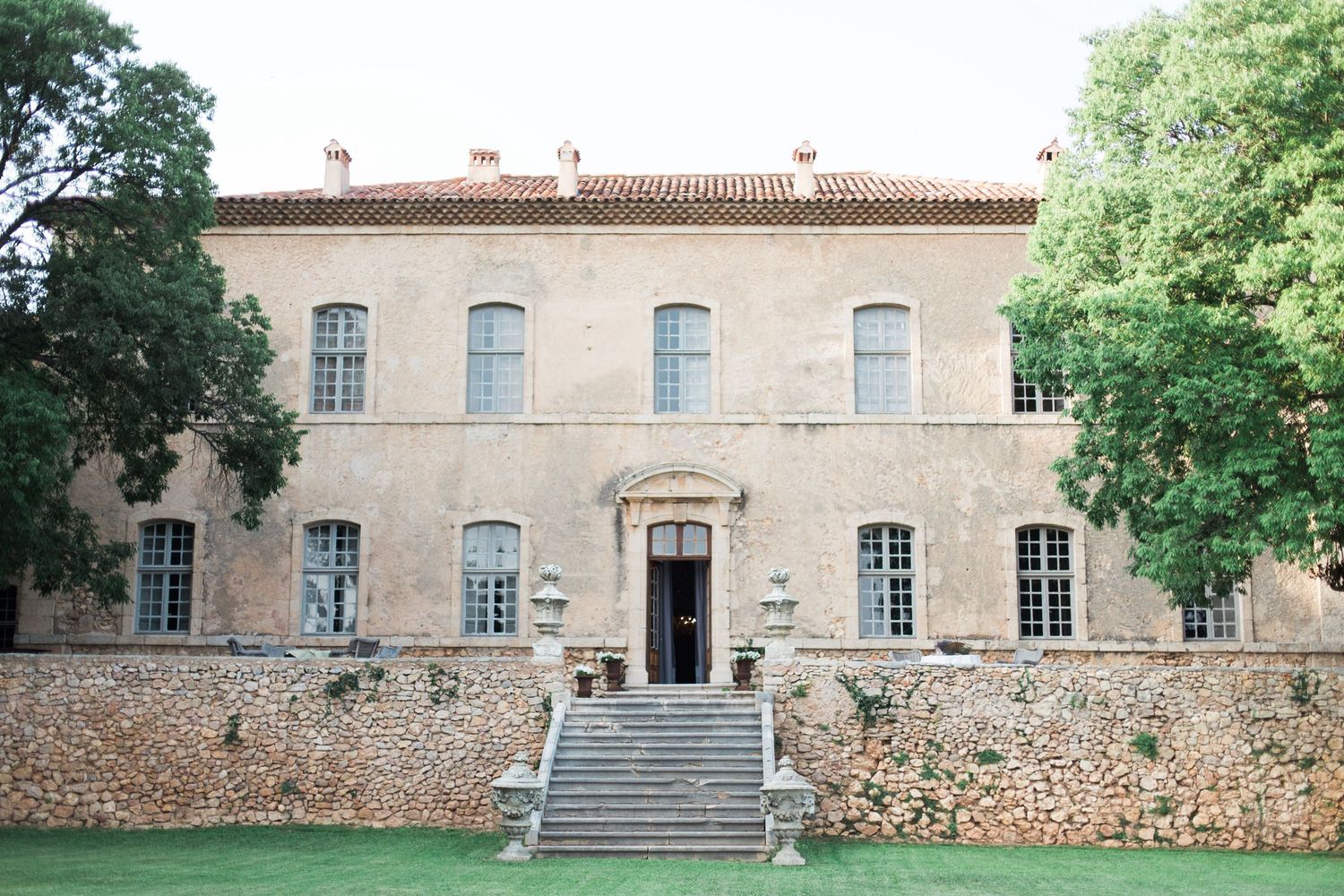 Elegant stone mansion with symmetrical windows and central staircase leading to entrance in a peaceful garden setting at chateau de moissac.