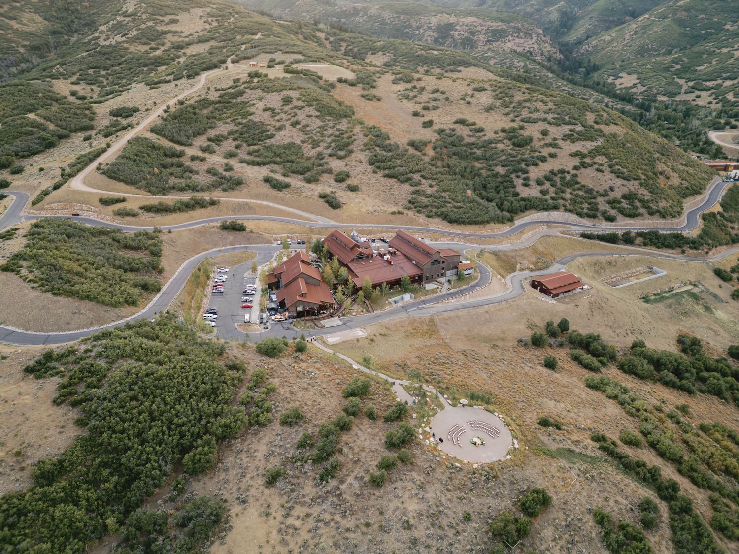 Aerial panoramic view of winding mountain roads and residential developments in a rugged desert landscape.