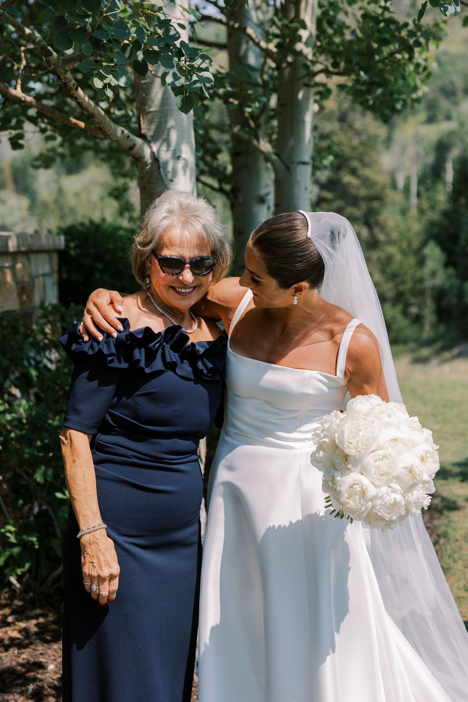 Three sequential photos show tender moments between a bride in white and a guest in navy at an outdoor wedding.