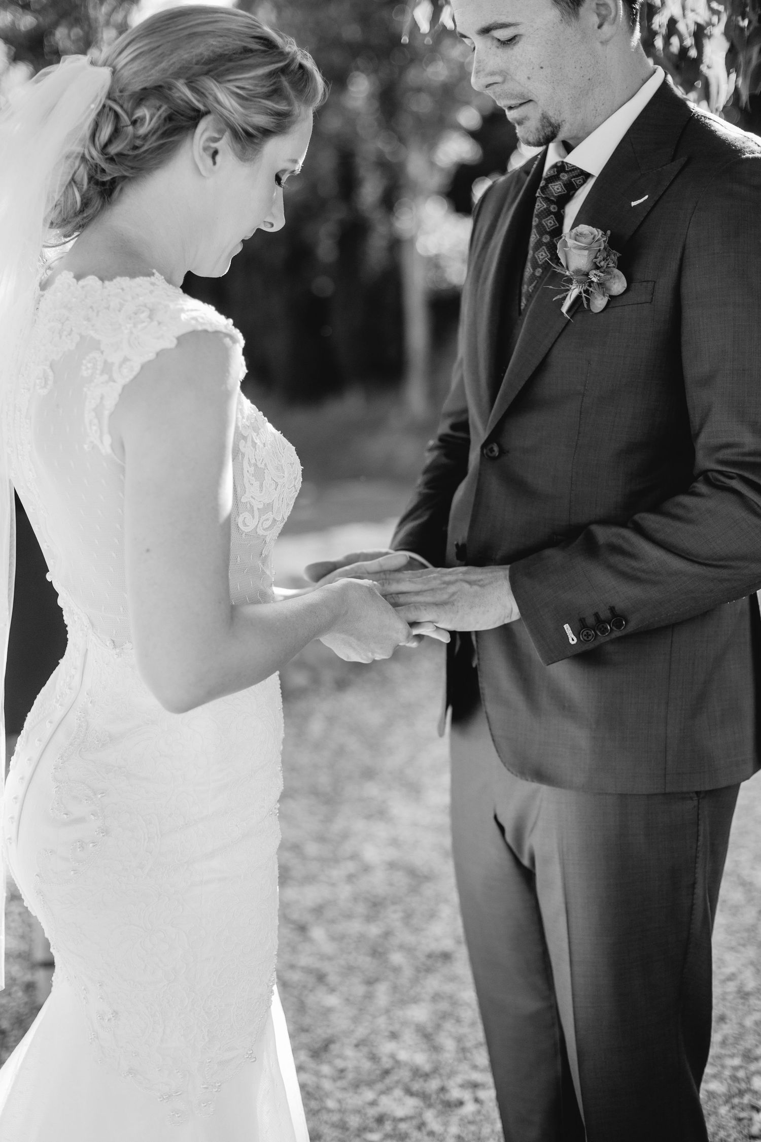 Close-up shot of wedding ceremony ring exchange with elegant lace dress details.