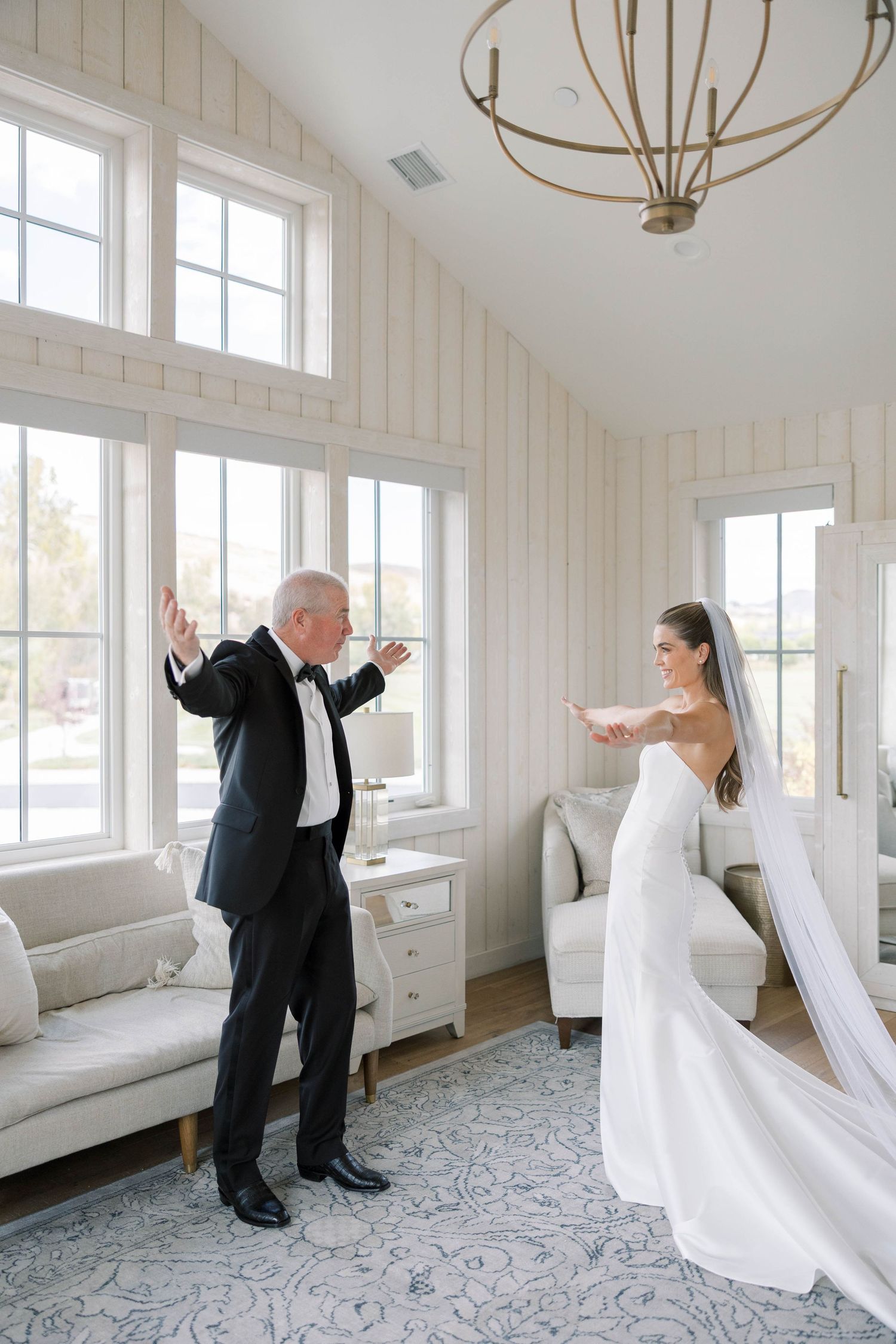 A series of joyful dance moments in a bright white room with elegant chandeliers during a wedding celebration.