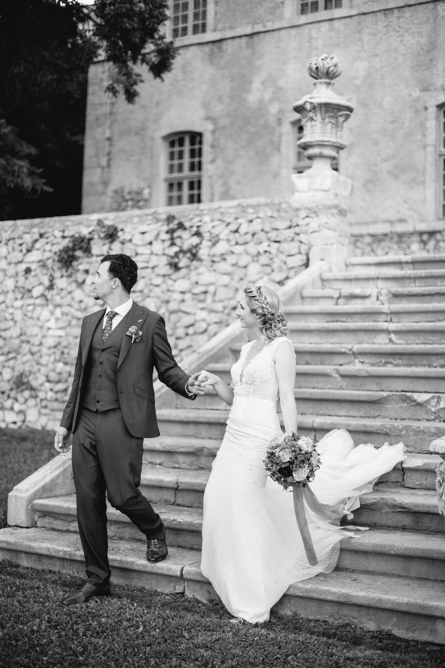 Wedding couple walking down grand outdoor stone steps at a historic venue at chateau de moissac.