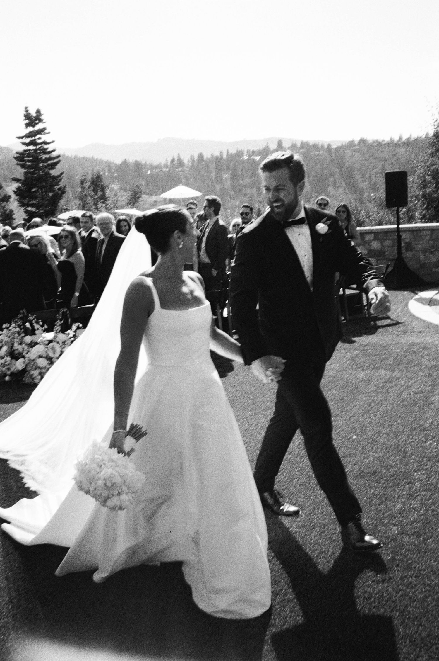 A sequence of black and white photos showing a couple dancing outdoors at a wedding with flowing white dress movements.